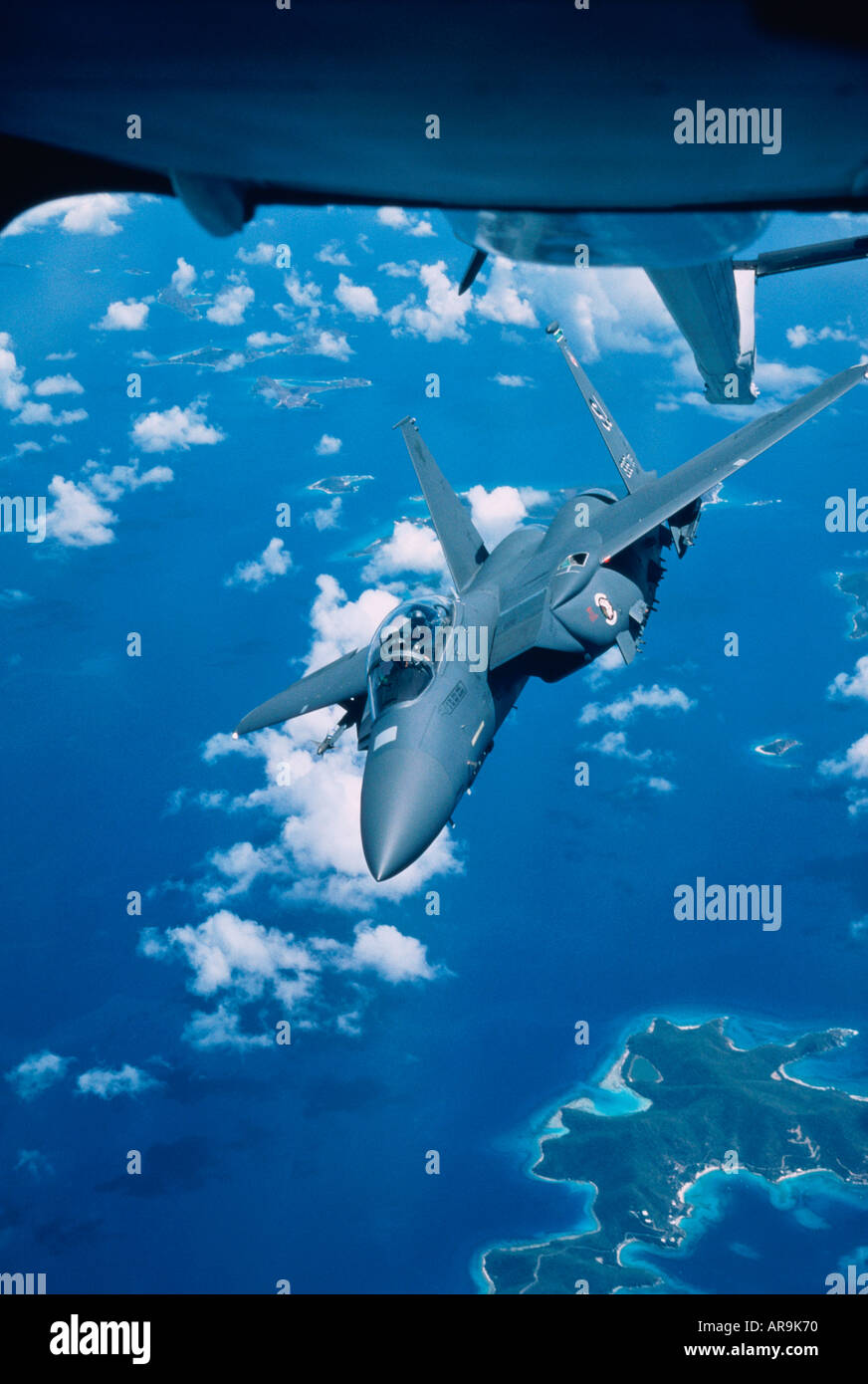 USAF Boeing F-15E  supersonic jet fighter bomber at high altitude flying over tropical islands Stock Photo