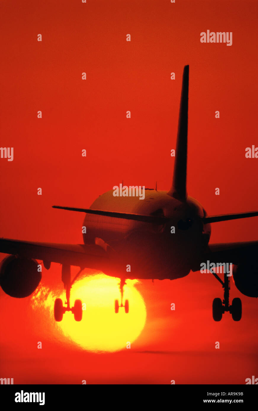 Airbus A320 jet airliner take off landing into sunset sunrise dusk undercarriage down jet thrust exhaust pollution silhouette Stock Photo