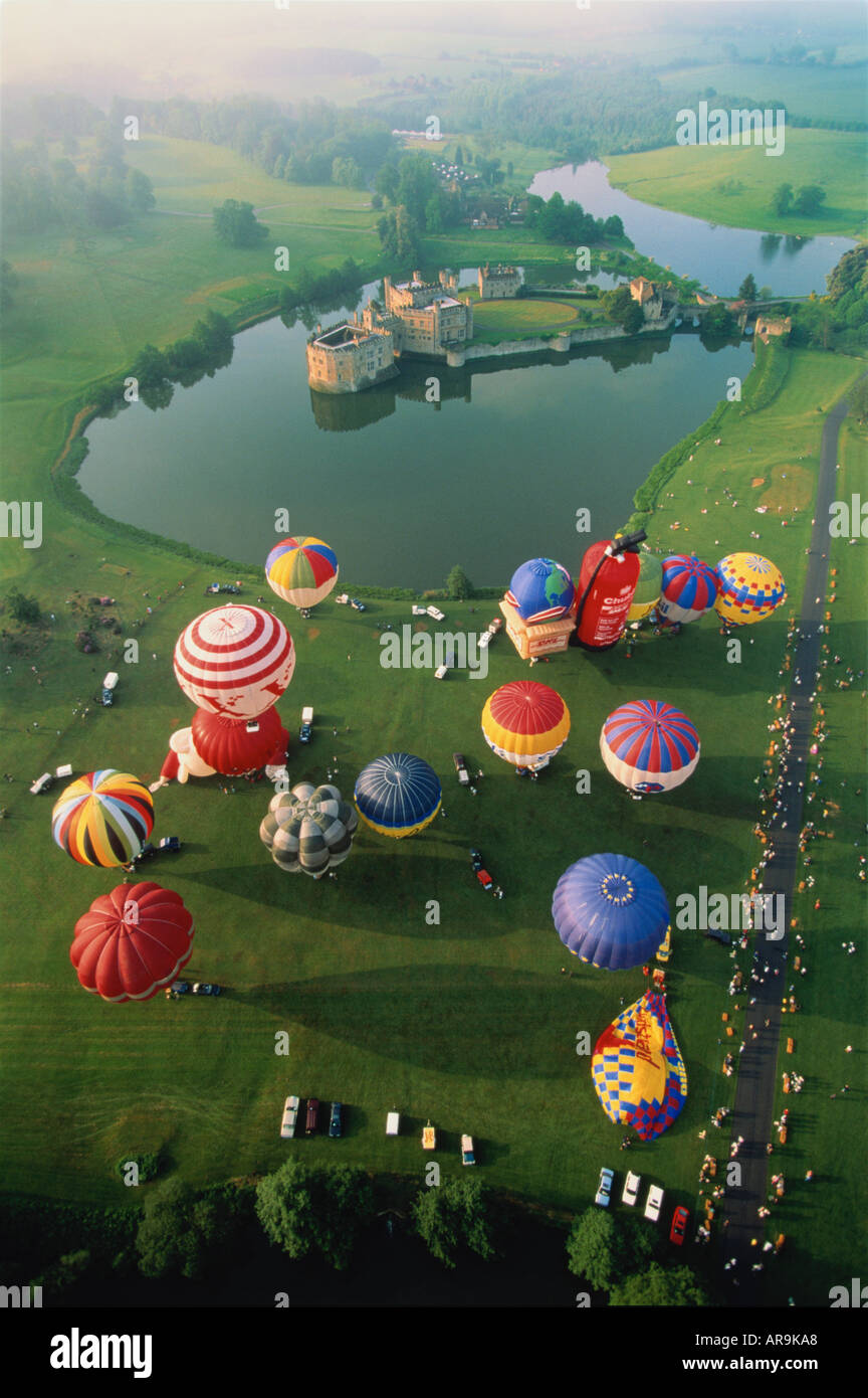 aerial view of hot air balloons launching take off over green grassy fields and lake Kent UK Leeds Castle in distance Stock Photo