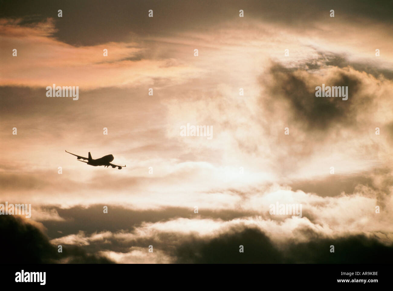 Boeing 747 jumbo jet airliner flying in the air cruising in a cloudy sky at sunset Stock Photo