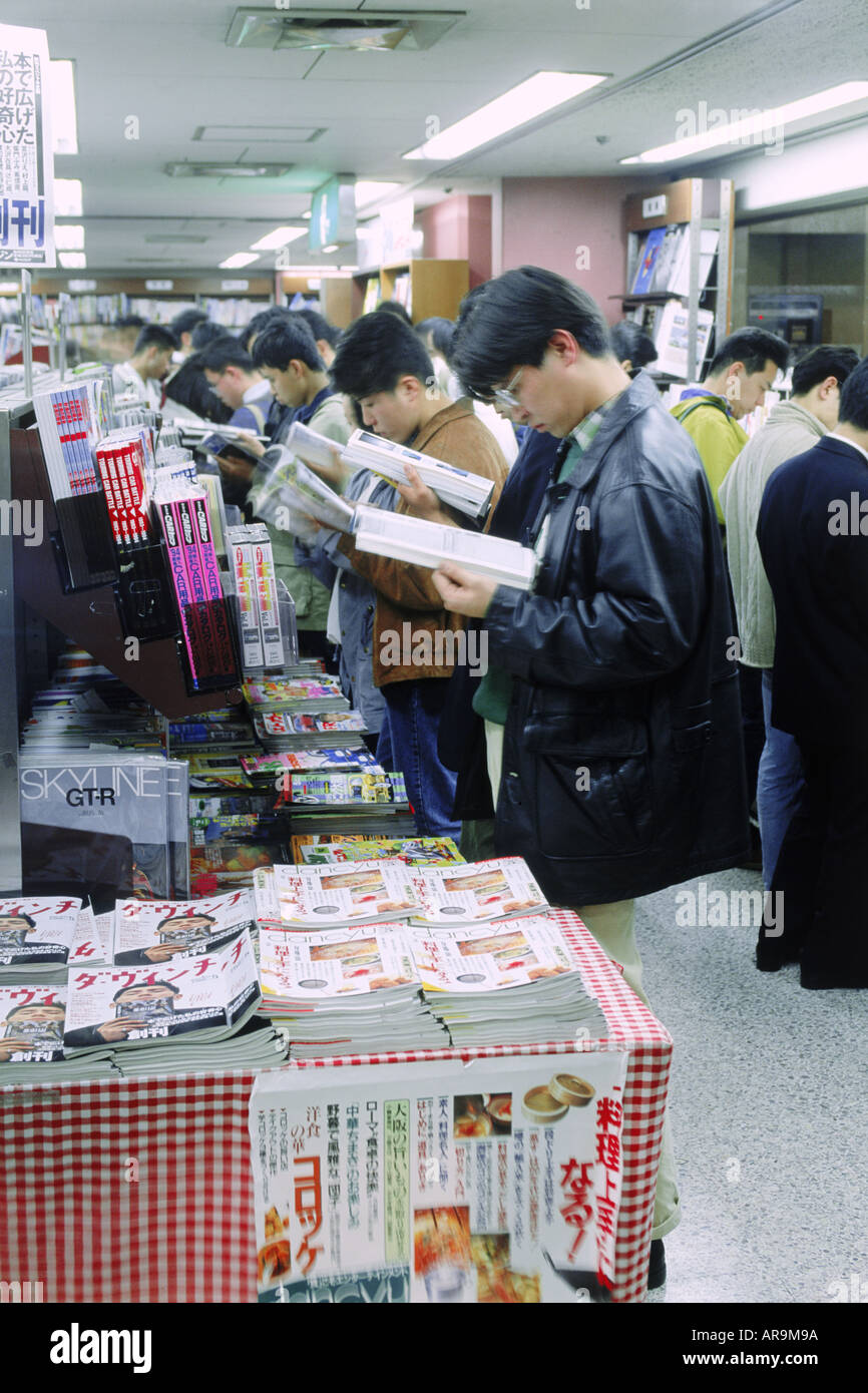 Young Japanese people filling aisles reading magazines in Tokyo bookstore Stock Photo