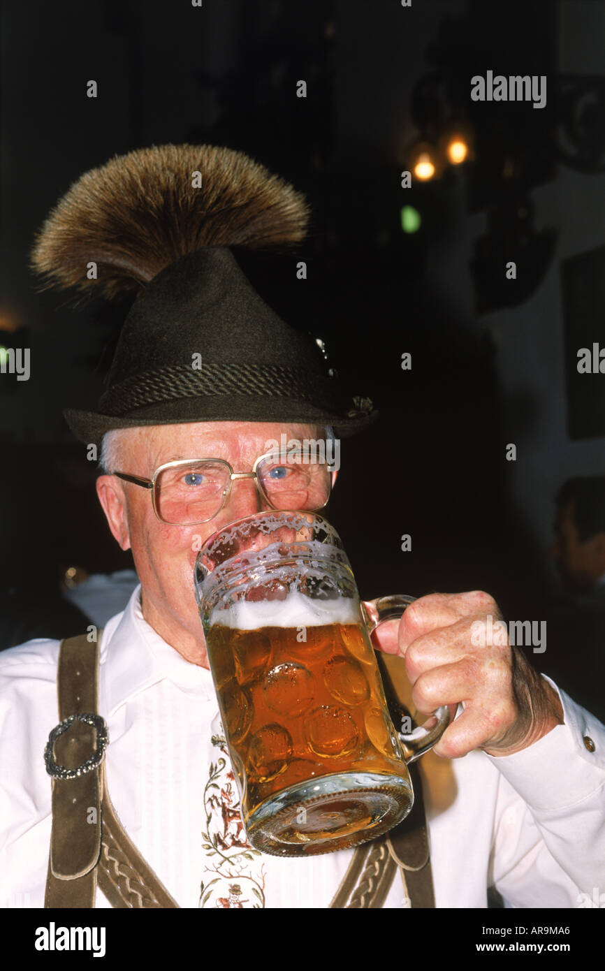 German man with fancy Bavarian hat holding mug of beer at Oktoberfest in Munich Stock Photo