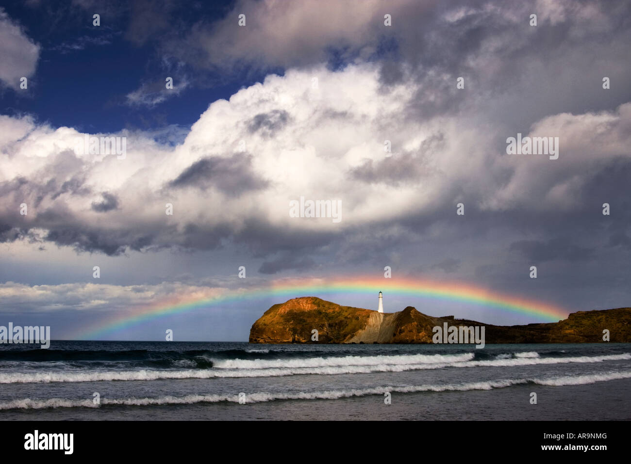 A passing rain shower creates a rainbow framing the lighthouse at