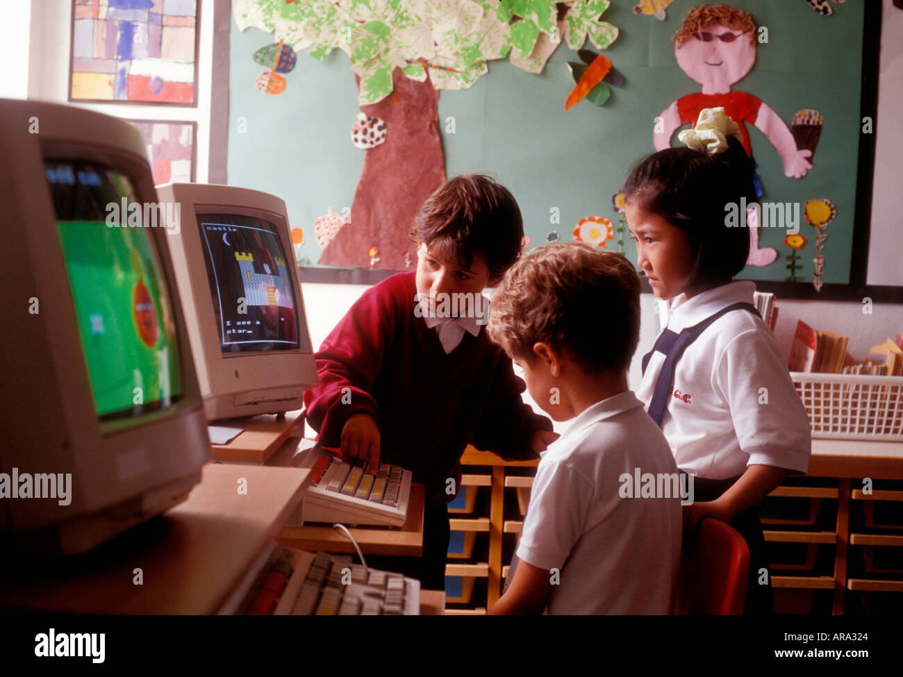 1990’s COMPUTER CLASS INFANT SCHOOL EARLY 90’s  COMPUTER SCREENS Group of 3 infant school children aged 4 to 6 years in early learning computer class Stock Photo