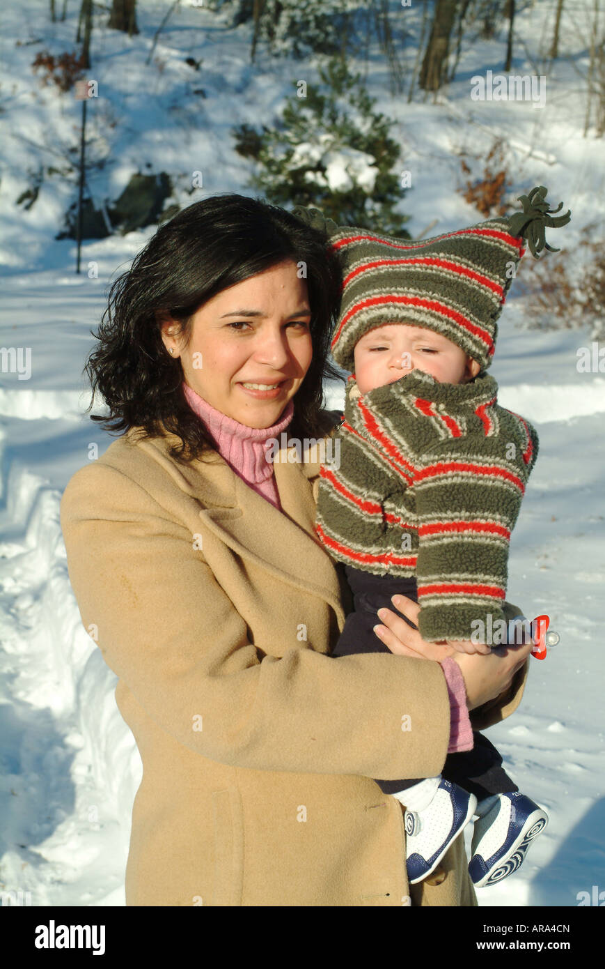Hispanic mother and six (6) month old grandson pose outside in the snow.  Melrose Massachusetts, USA Stock Photo