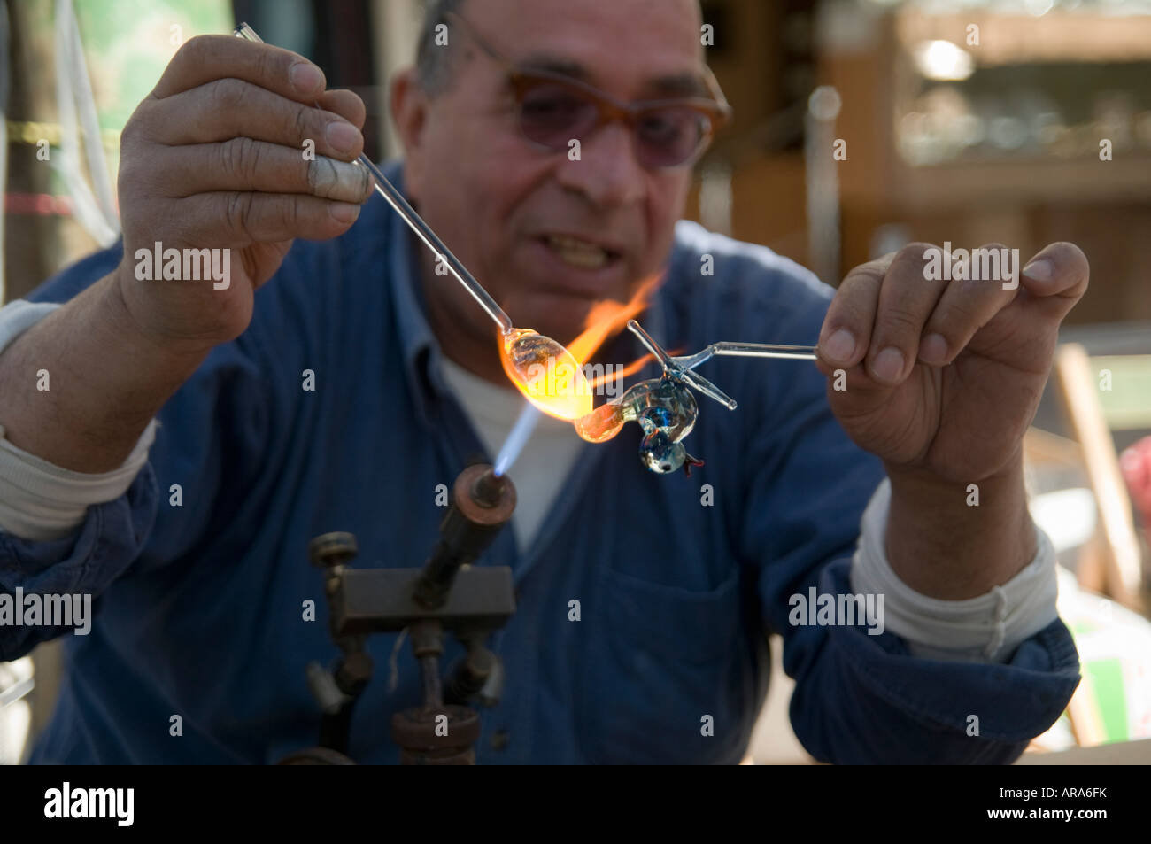 Glass artist melting and re shaping glass with the aid of a Bunsen