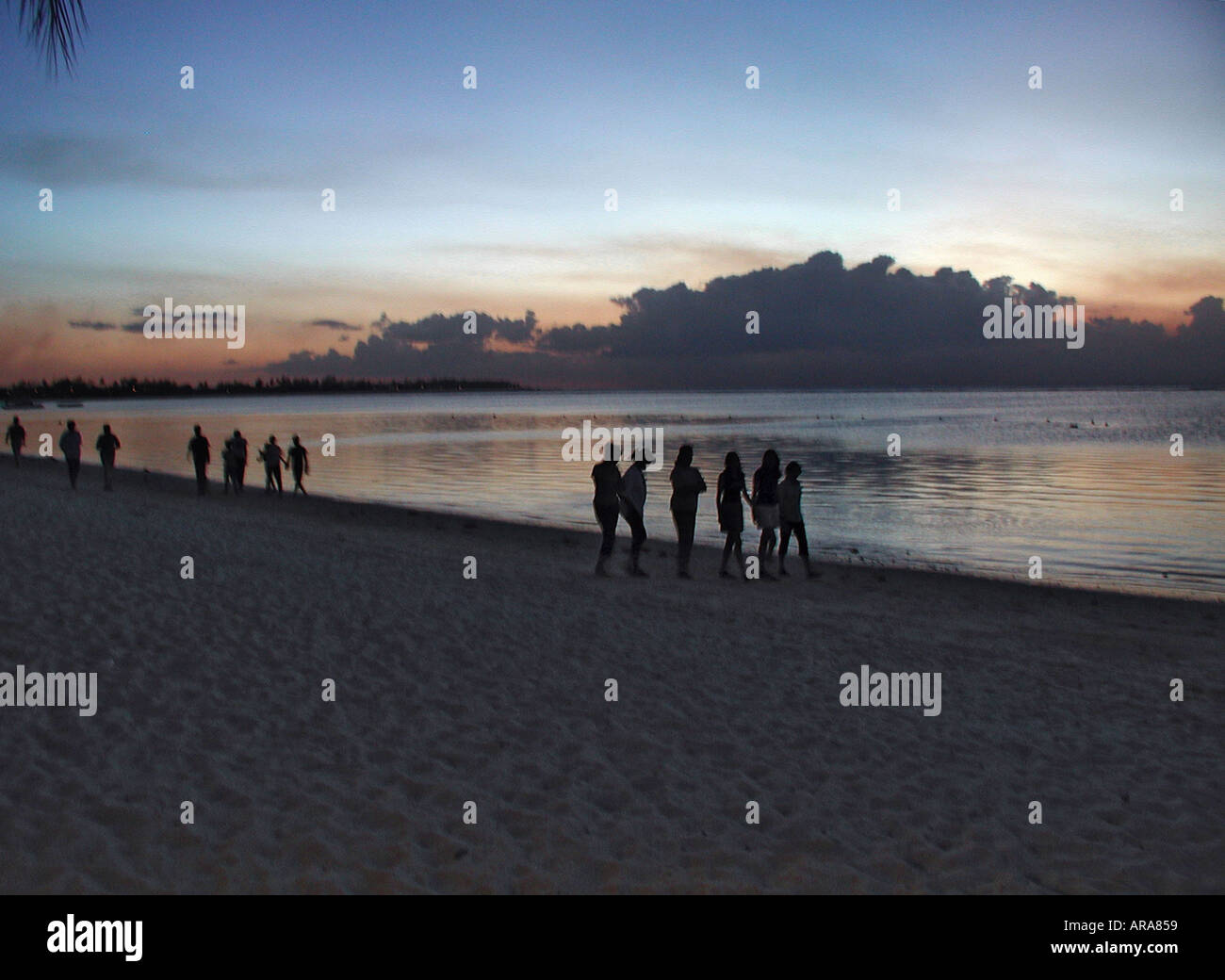 Figures walking along the beach as the sun goes down Trou au Biches ...