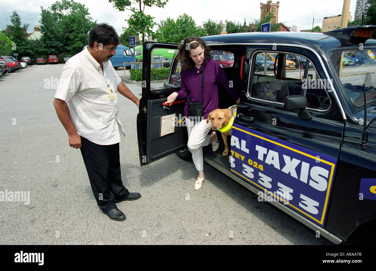 Visually impaired young woman emerging from taxi assisted by driver