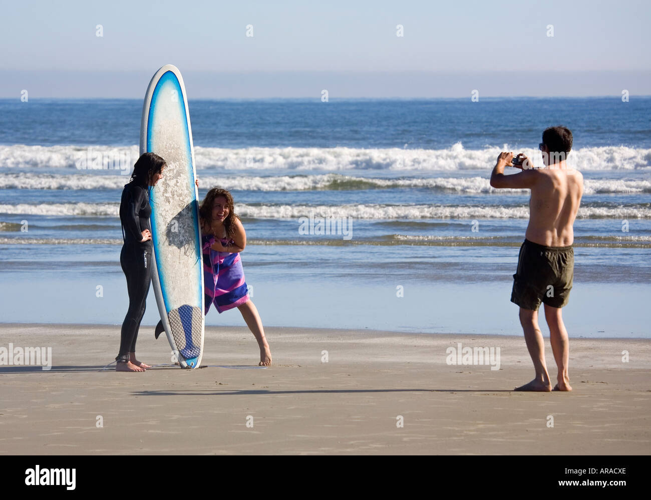 Two female surfers posing for a photograph on Long Beach Pacific Rim national park reserve Vancouver island Canada Stock Photo