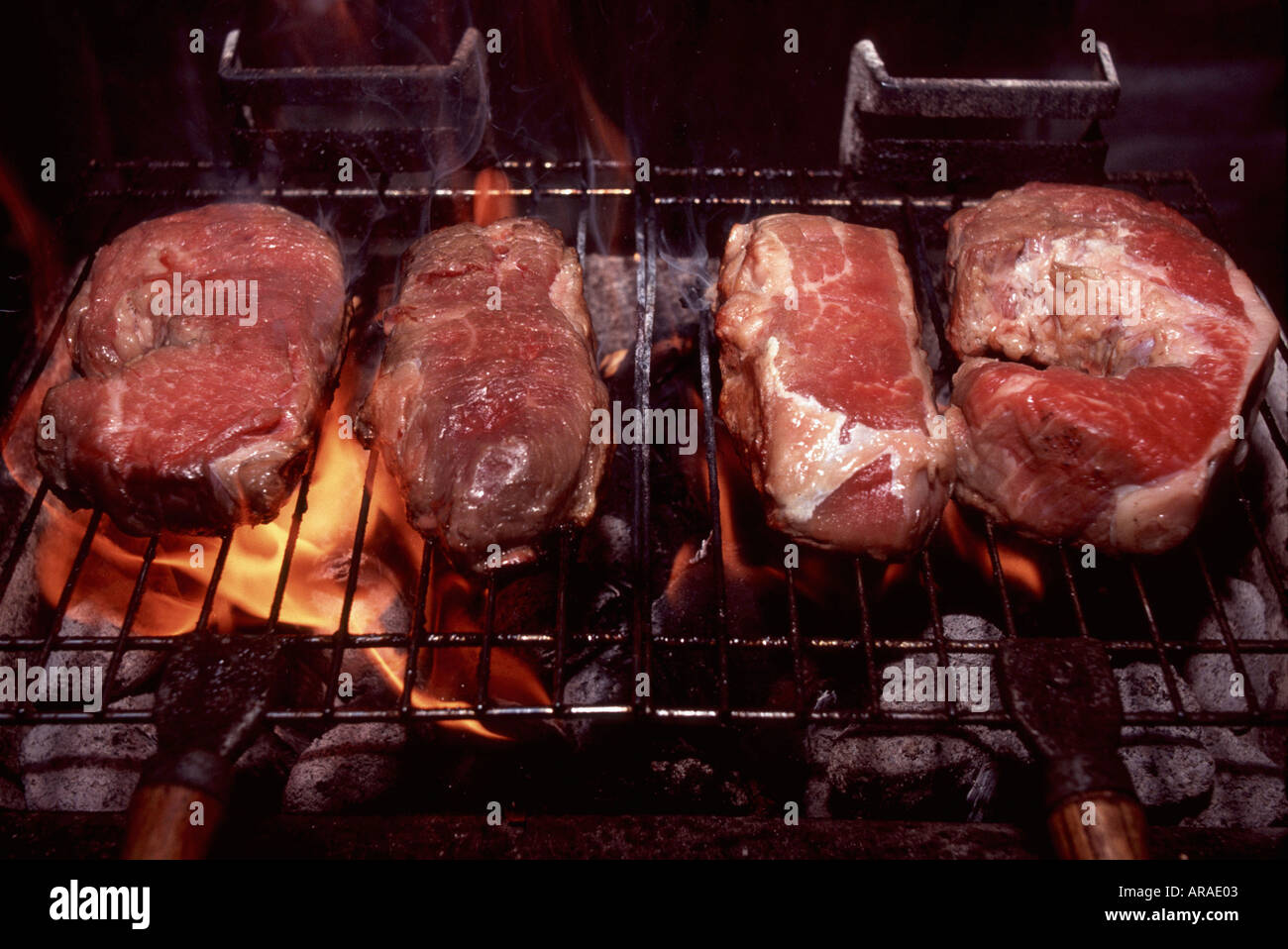 Some juicy steaks are being prepared over hot coals in a Hibachi