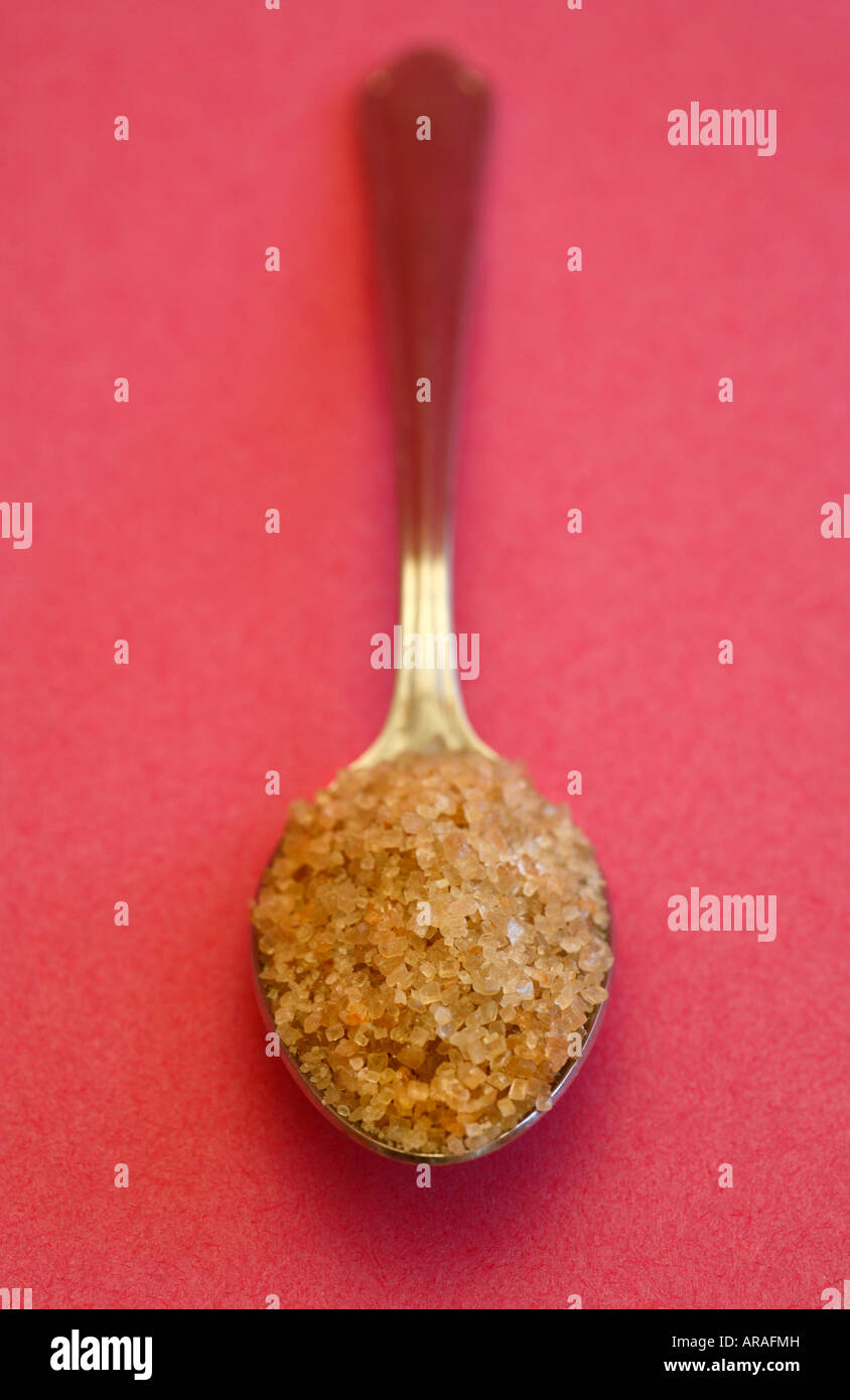 Spoonful of demerara sugar against a pink background. Stock Photo