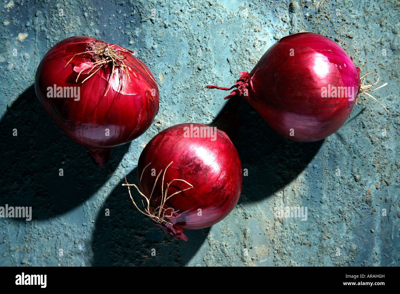 Red onions on a rustic blue background. Stock Photo