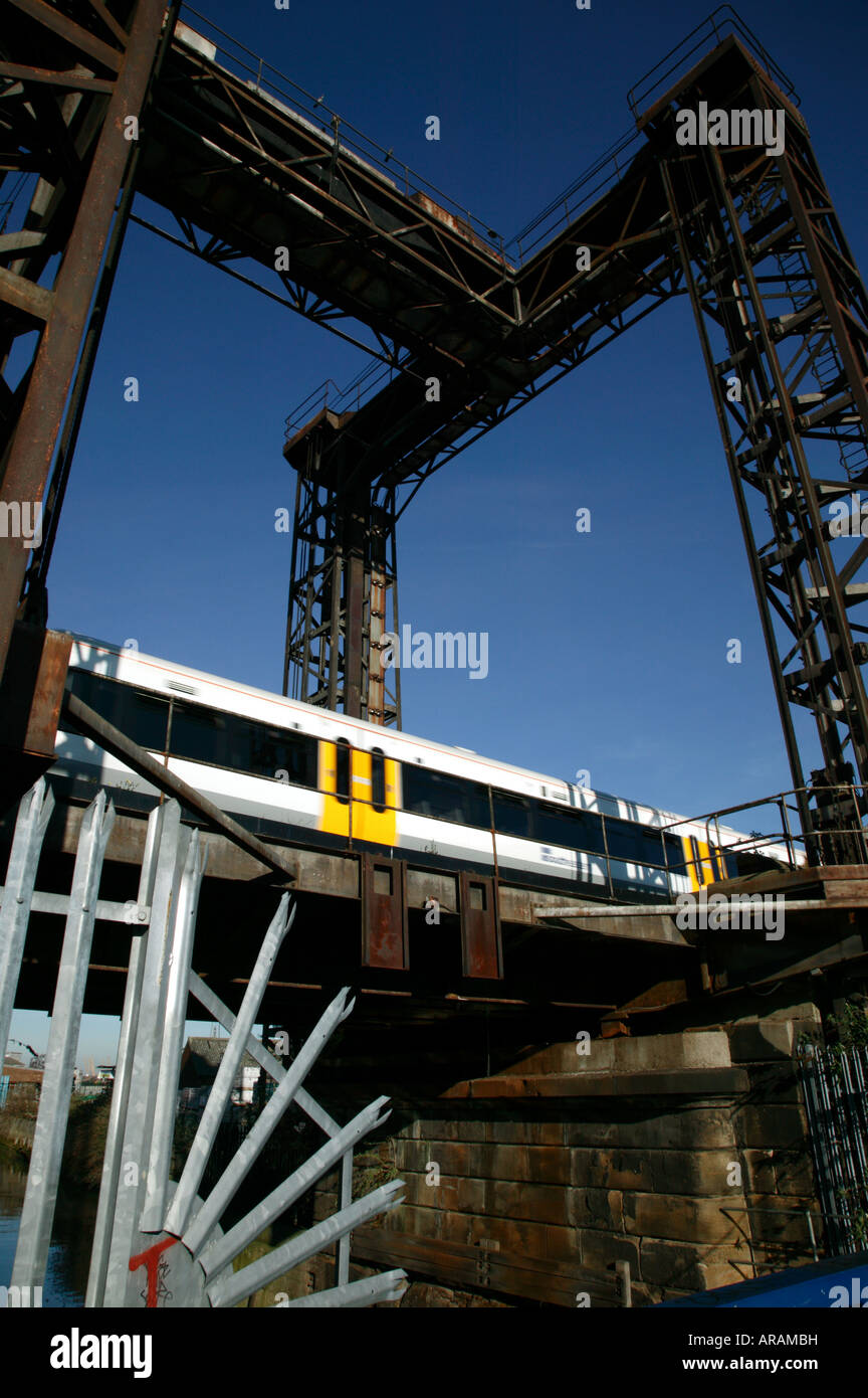 Mainline Train passing over a Bridge alongside  Ha' Penny Hatch Footbridge , Deptford Creek, Stock Photo