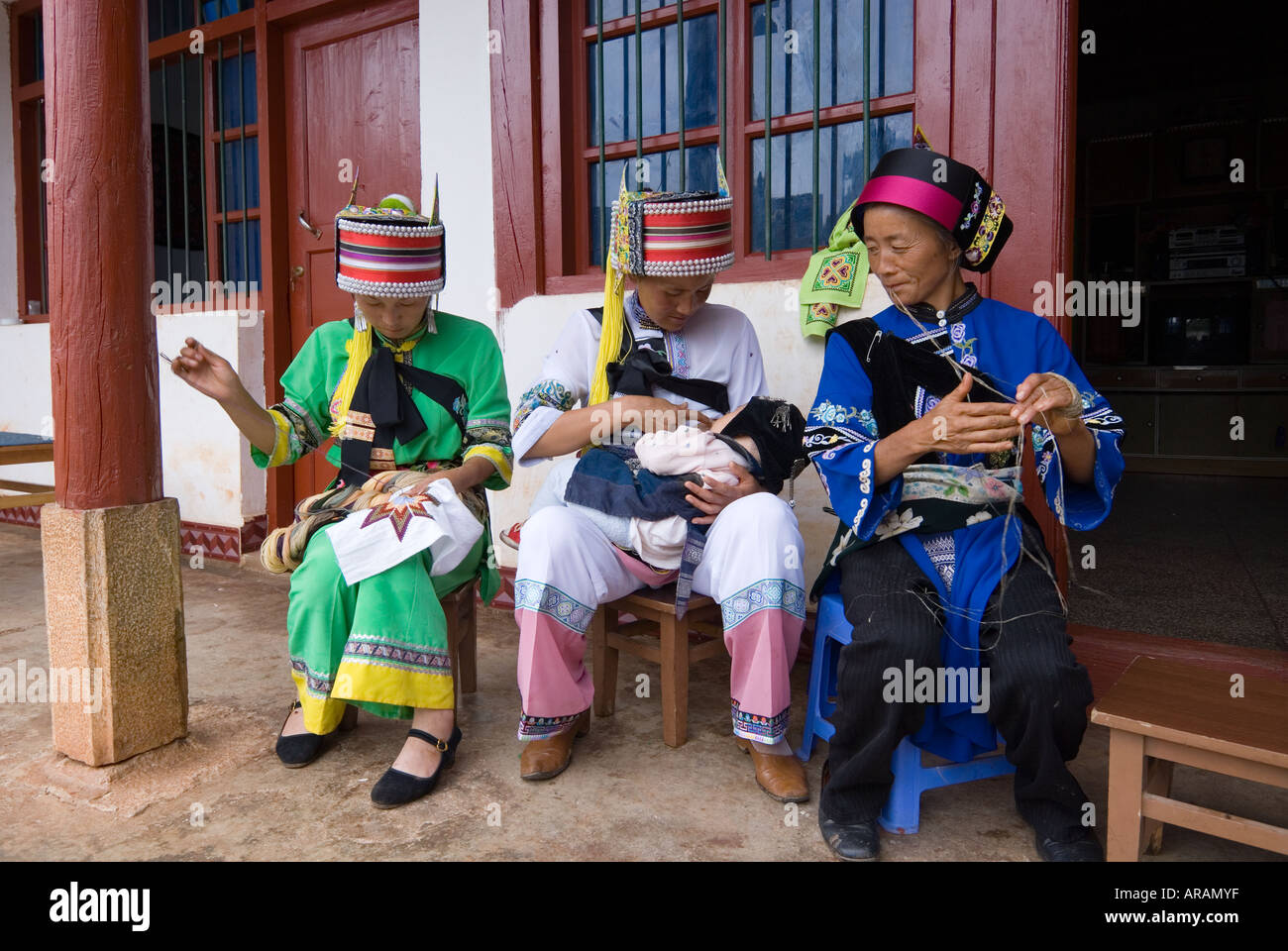 Three generations of Sani ethnic minority women stitch nurse and prepare thread in Azhuodi village Shilin County Yunnan China Stock Photo