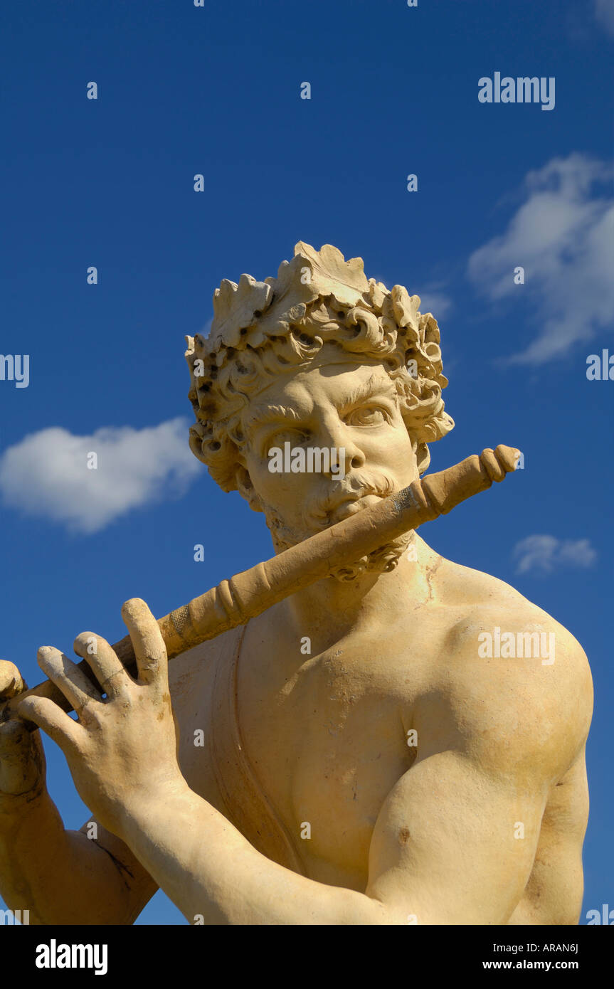 Statue of Pan playing his flute stands in contrast to the sky and clouds. This image is a good representation of antiquity. Stock Photo