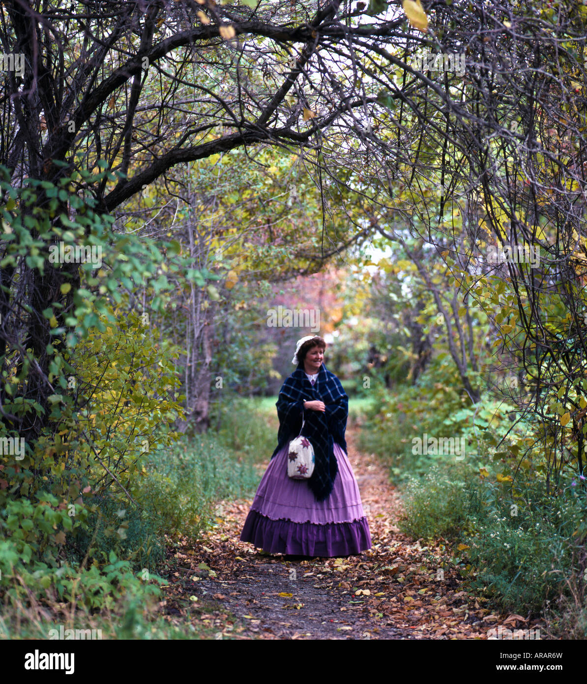 Woman in 19th Century period dress on a farm outdoors at the tree orchard Stock Photo