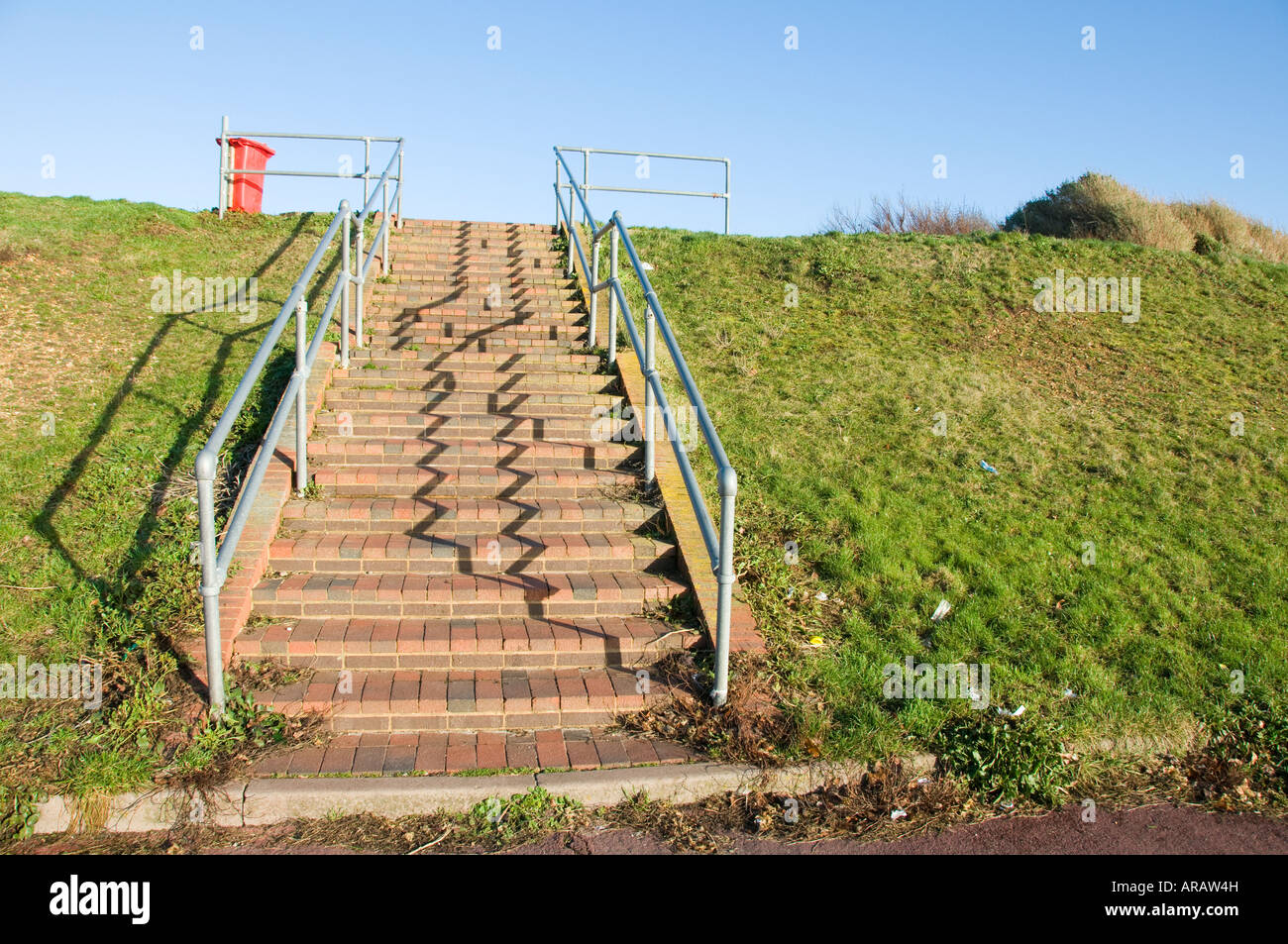 Steps with metal handrails casting shadow from low sunlight Stock Photo