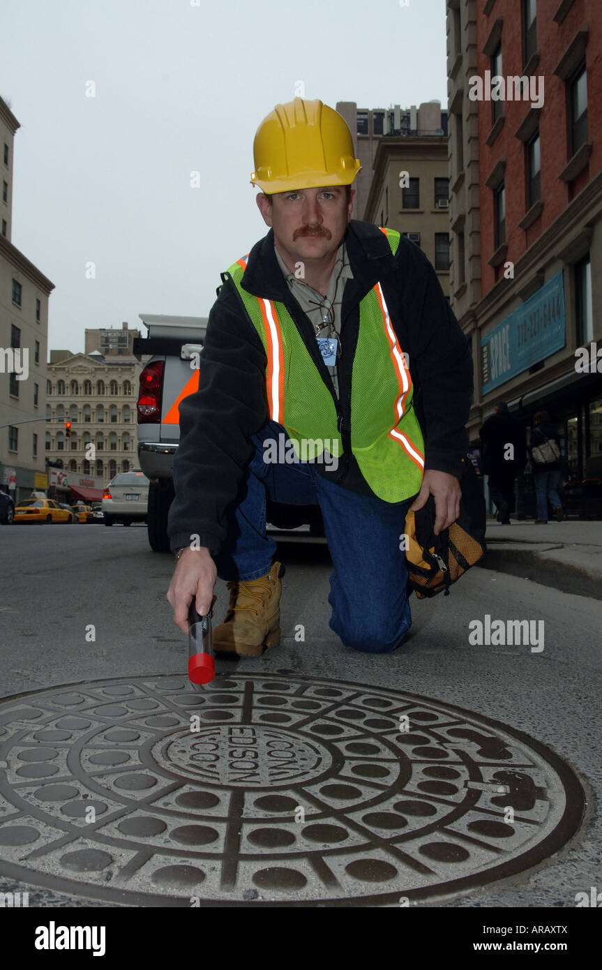 Employee of Con Edison power company in NYC uses a sensor to measure for dangerous stray voltage on a manhole cover Stock Photo