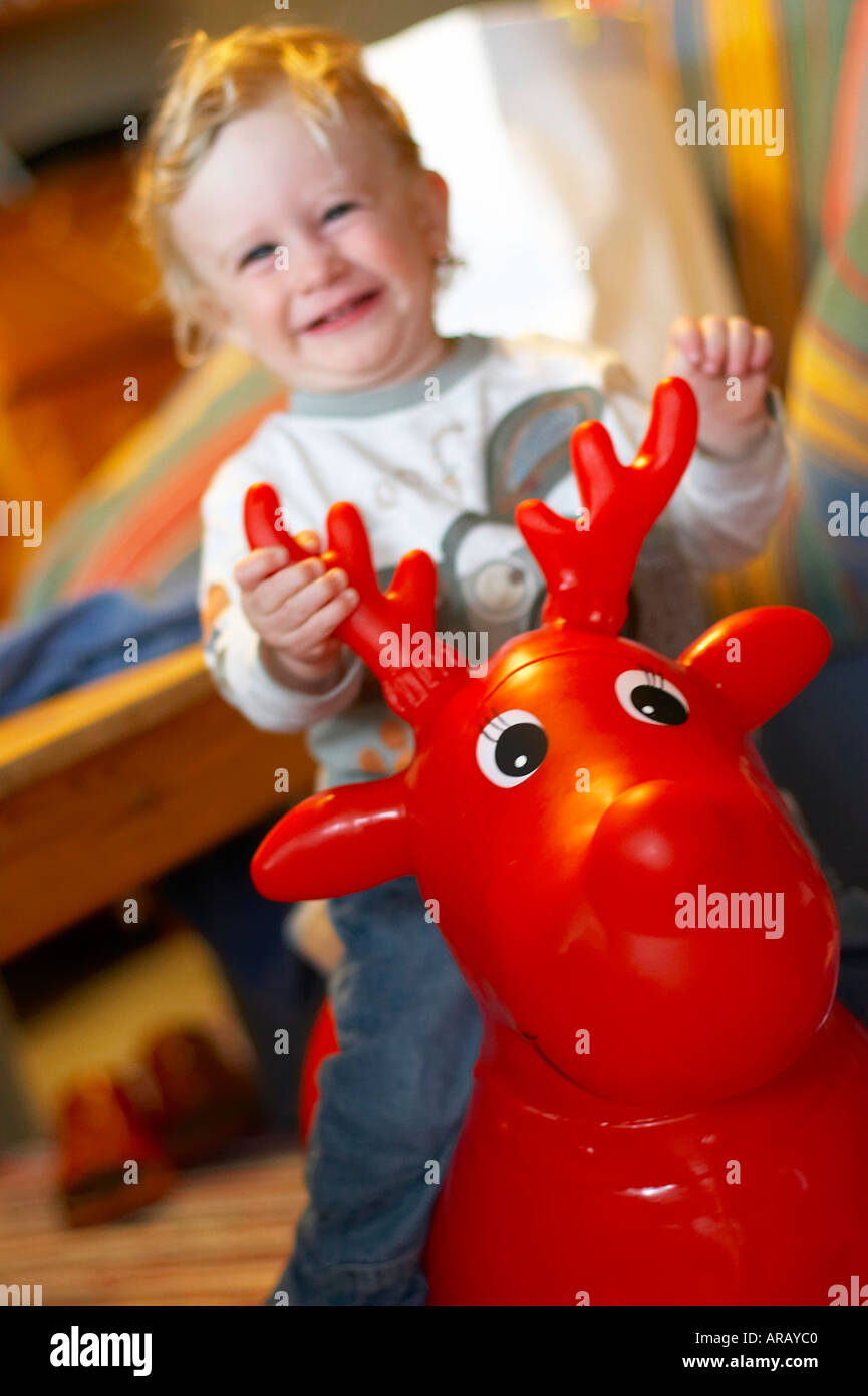 baby sitting on red inflatable elk Stock Photo