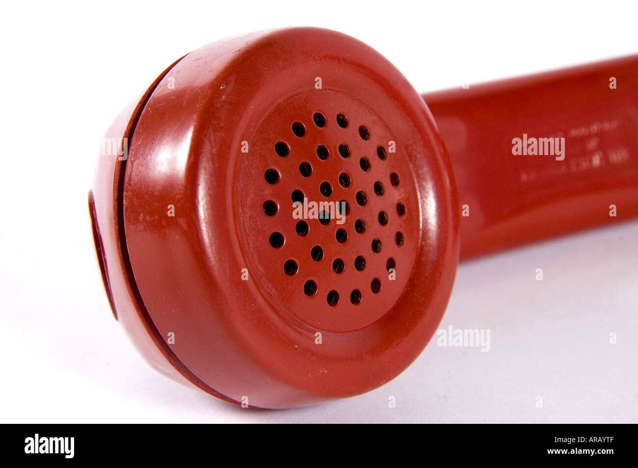 a red dial telephone receiver microphone end shot from above on white