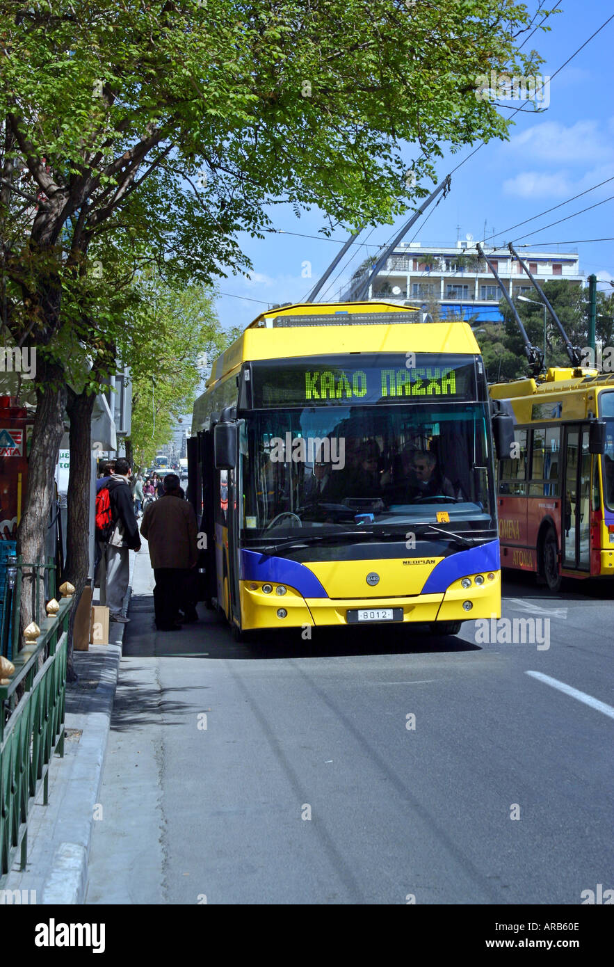 Bus cable yellow public Athens transport tram road people passengers side day electricity old Kalo Pasxa Happy Easter blue tree Stock Photo