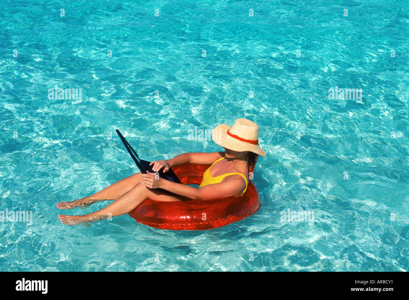 Woman sunbathing on air mattress with laptop computer Stock Photo