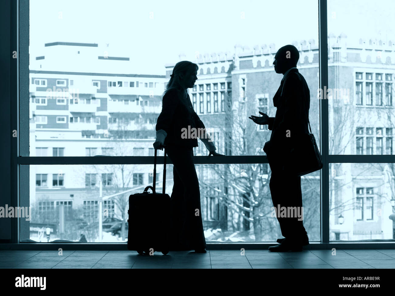 Two business colleagues silhouetted in a large window. Stock Photo