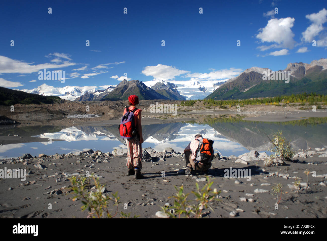 Hikers on foot of Kennicott glacier and glacial lake at McCarthy Wrangell Saint Elias National Park Alaska Stock Photo