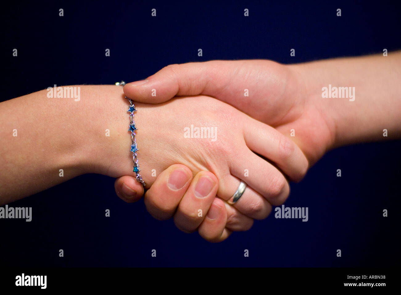 Male and Female Informal Handshake, against blue background Stock Photo