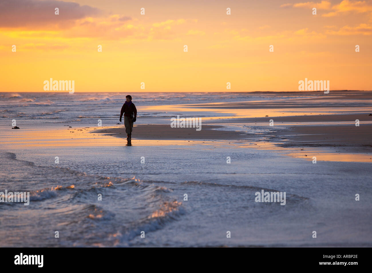 Woman walking alone on beach hi-res stock photography and images - Alamy