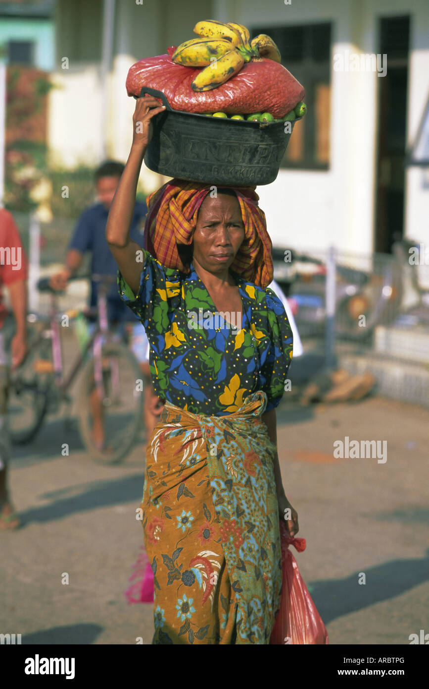 Woman carrying basket of fruit on her head, Sape, Sumbawa, Nusa Tenggara group, Indonesia, Southeast Asia,  Asia Stock Photo