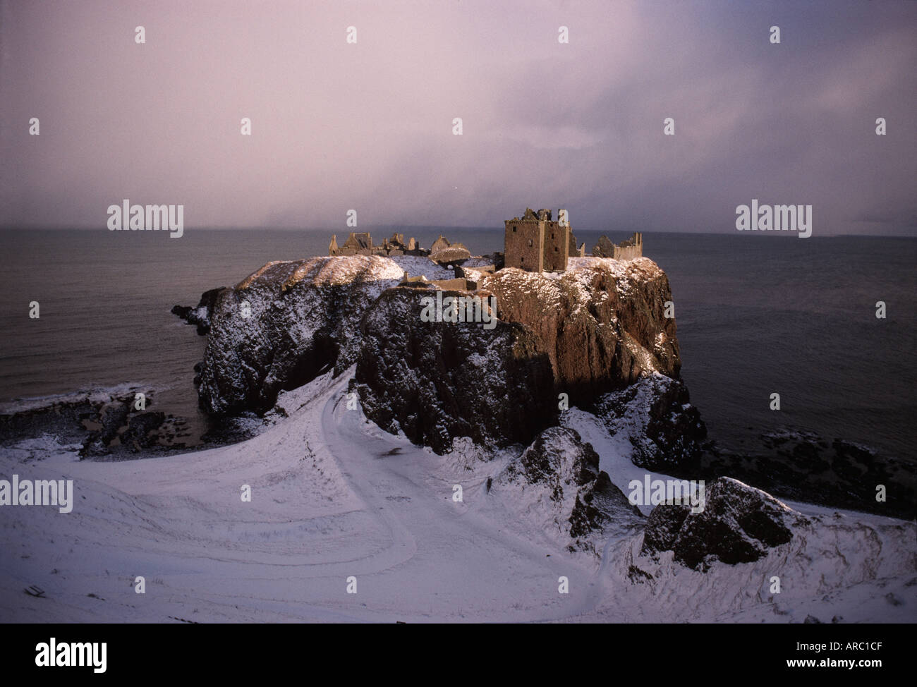 Dunnottar Castle under snow with approaching storm clouds over the sea Scotland Stock Photo