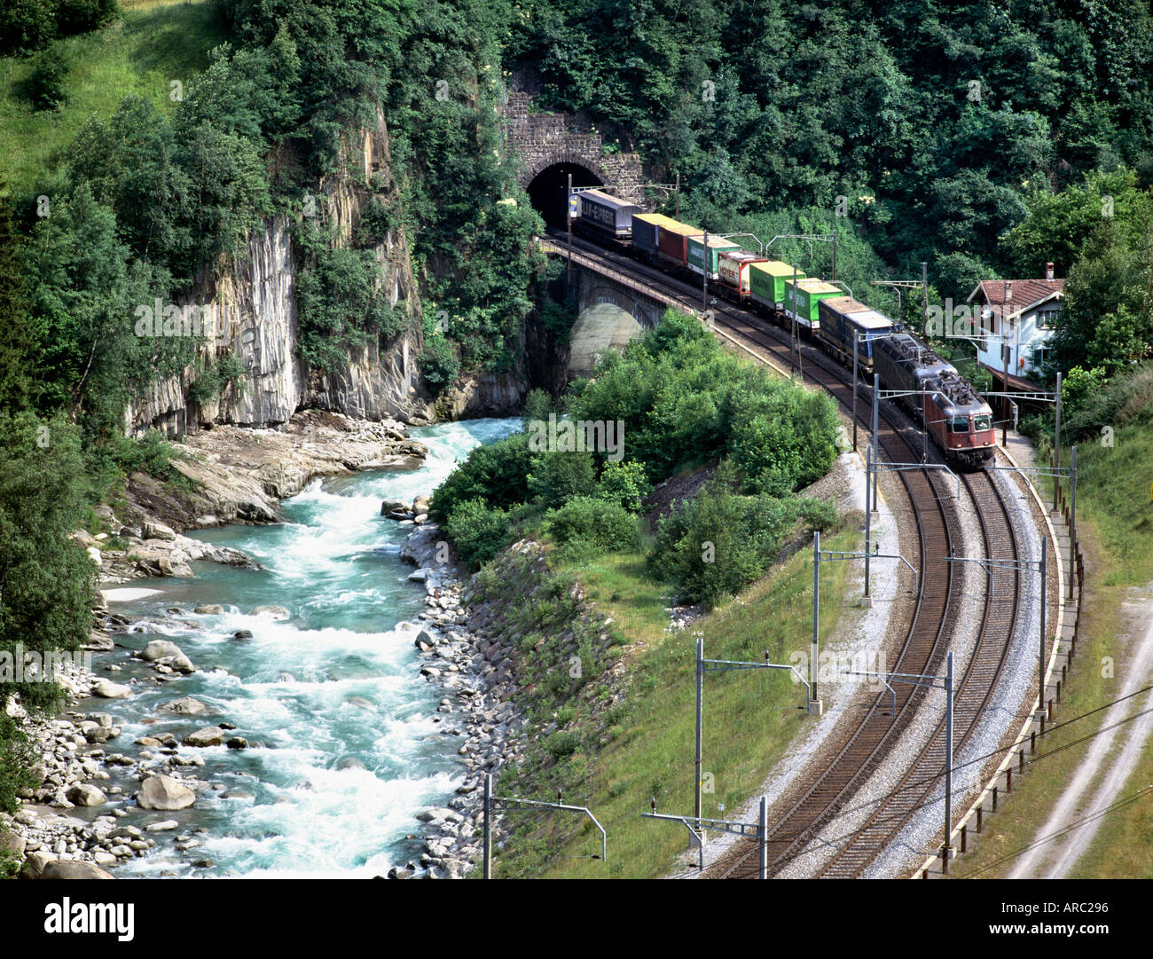 A freight train crosses the River Reuss near Wassen in the Swiss Alps Stock Photo