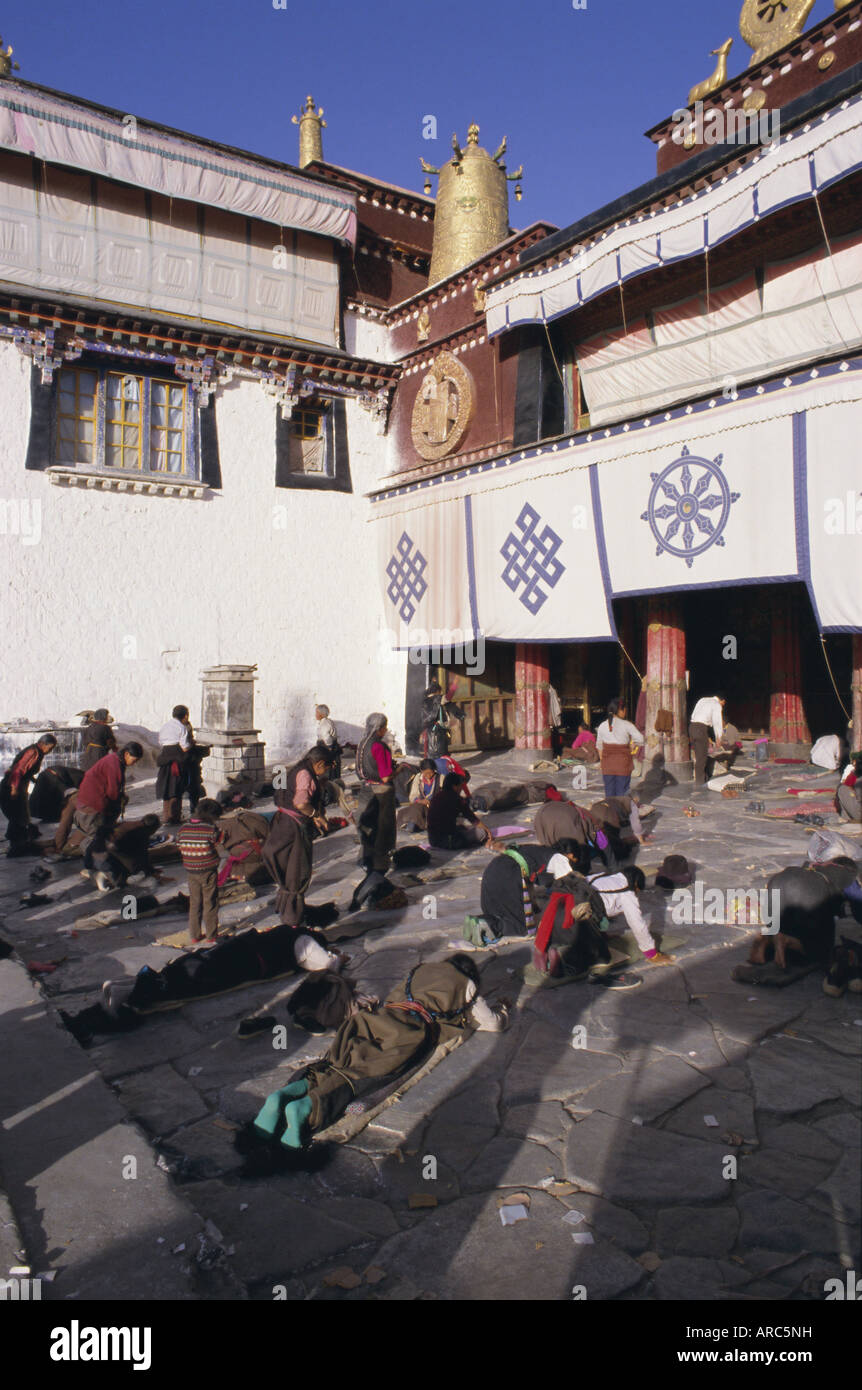 Pilgrims prostrating outside the Jokhang Temple, Lhasa, Tibet, China, Asia Stock Photo