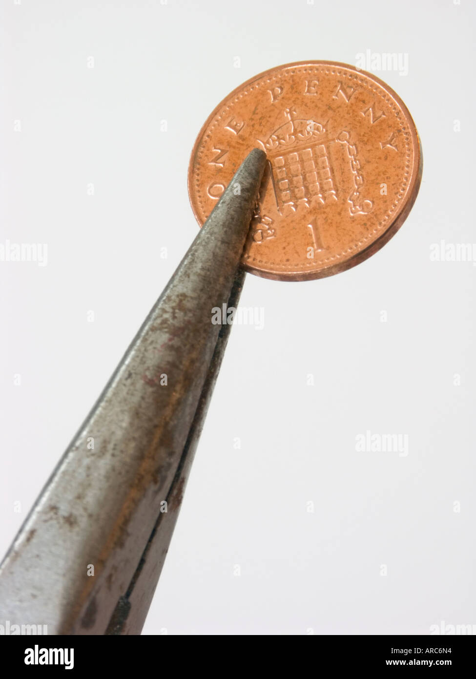 Penny pinching. A penny gripped by pliers Stock Photo Alamy