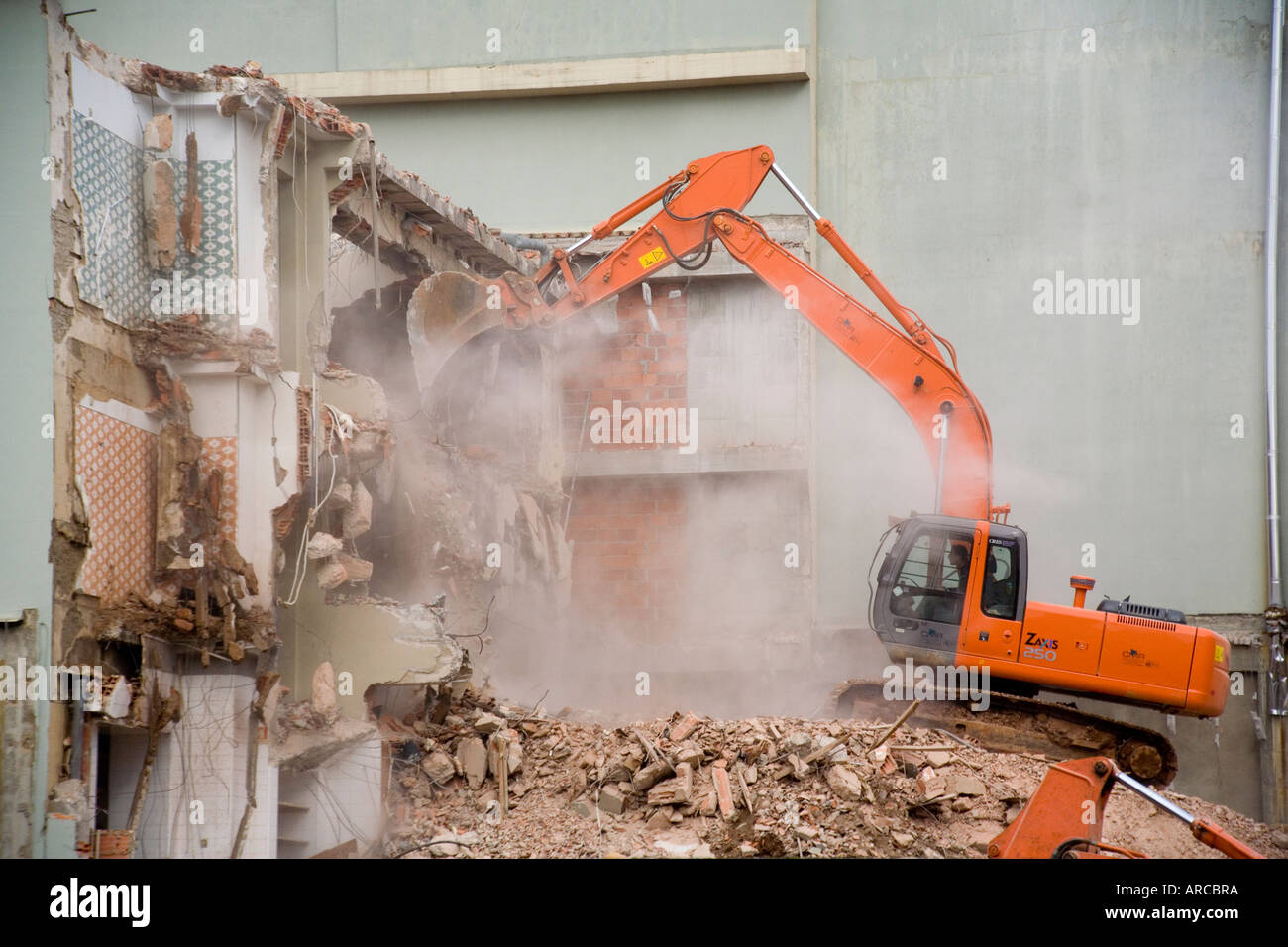 A backhoe is used to demolish a reinforced concrete building in Fatima Portugal Stock Photo