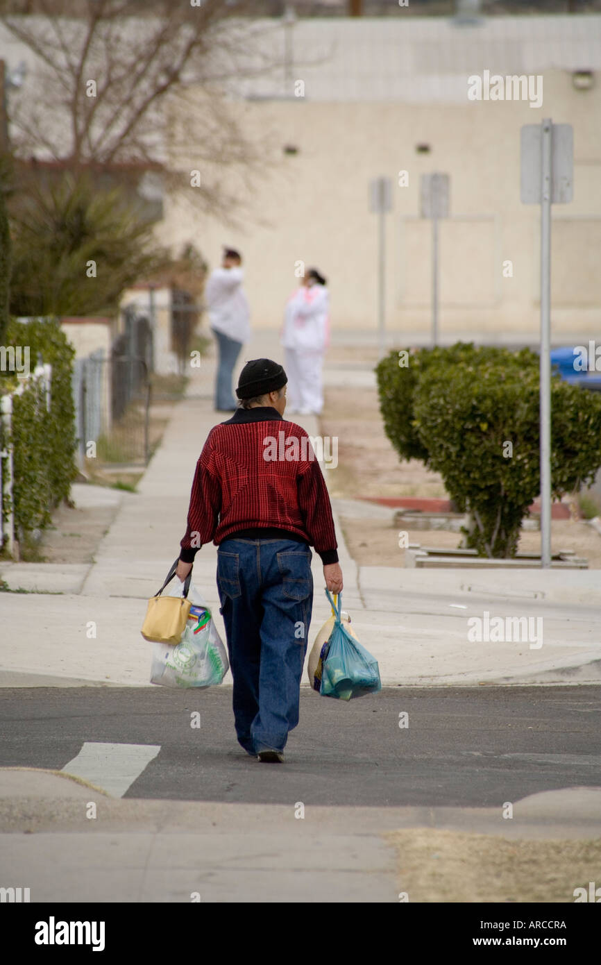 An Asian woman carries donated food for a Christmas dinner provided by a program at a low income and homeless shelter in Barstow Stock Photo
