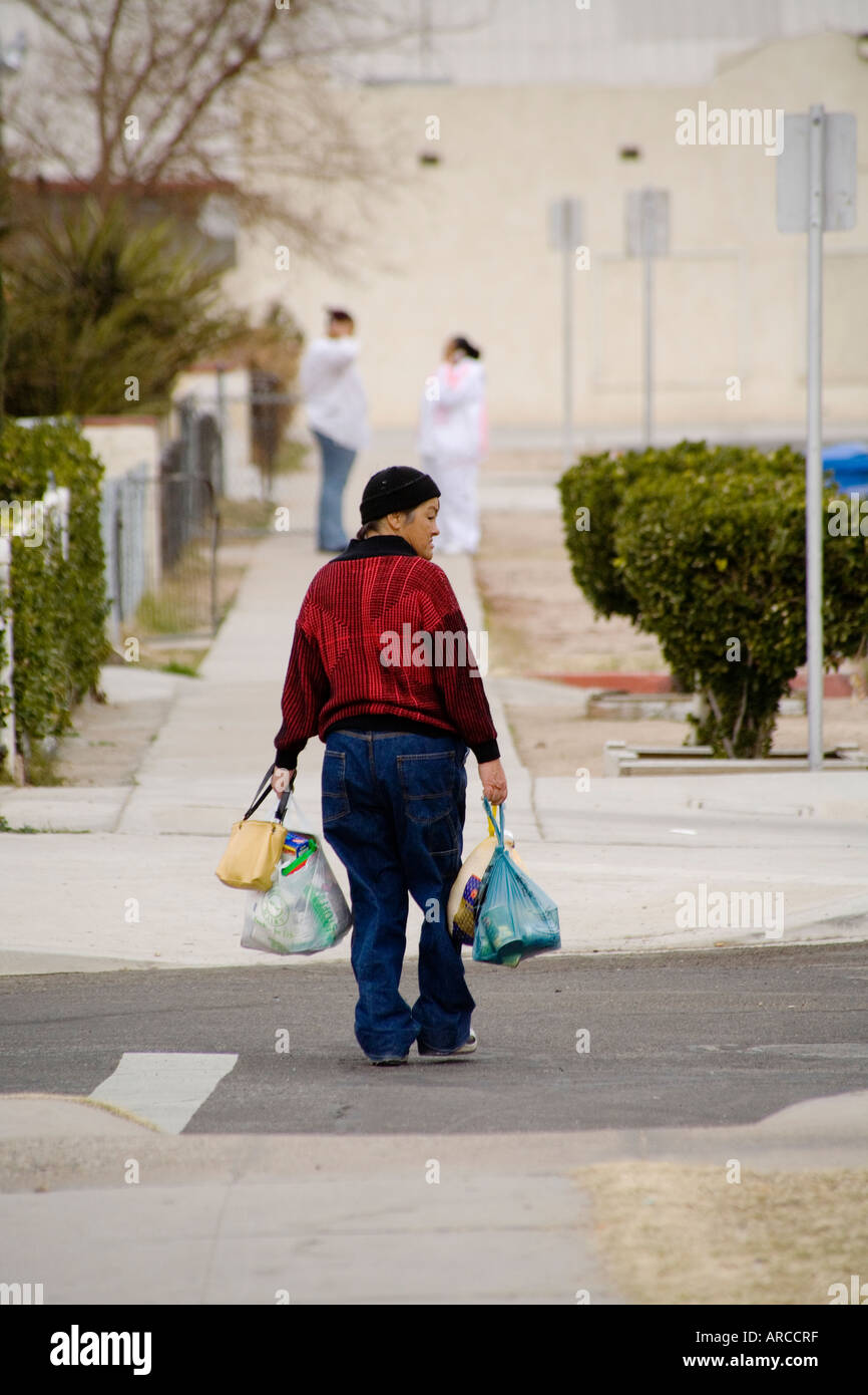An Asian woman carries donated food for a Christmas dinner provided by a program at a low income and homeless shelter in Barstow Stock Photo