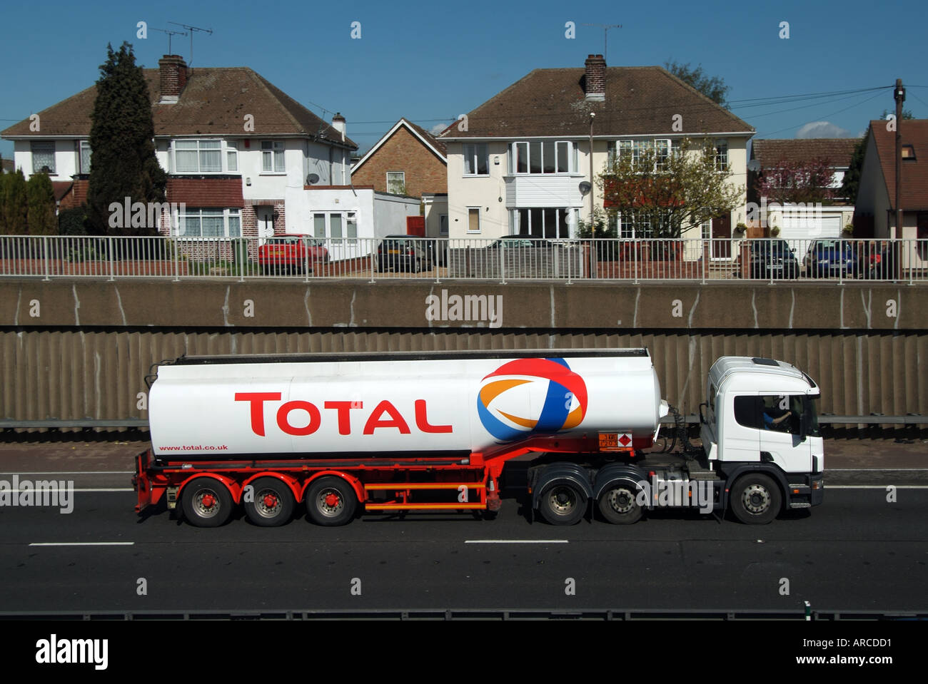 Lorry on dual carriageway trunk road in cutting adjacent residential properties with separate service road shows retaining wall Stock Photo