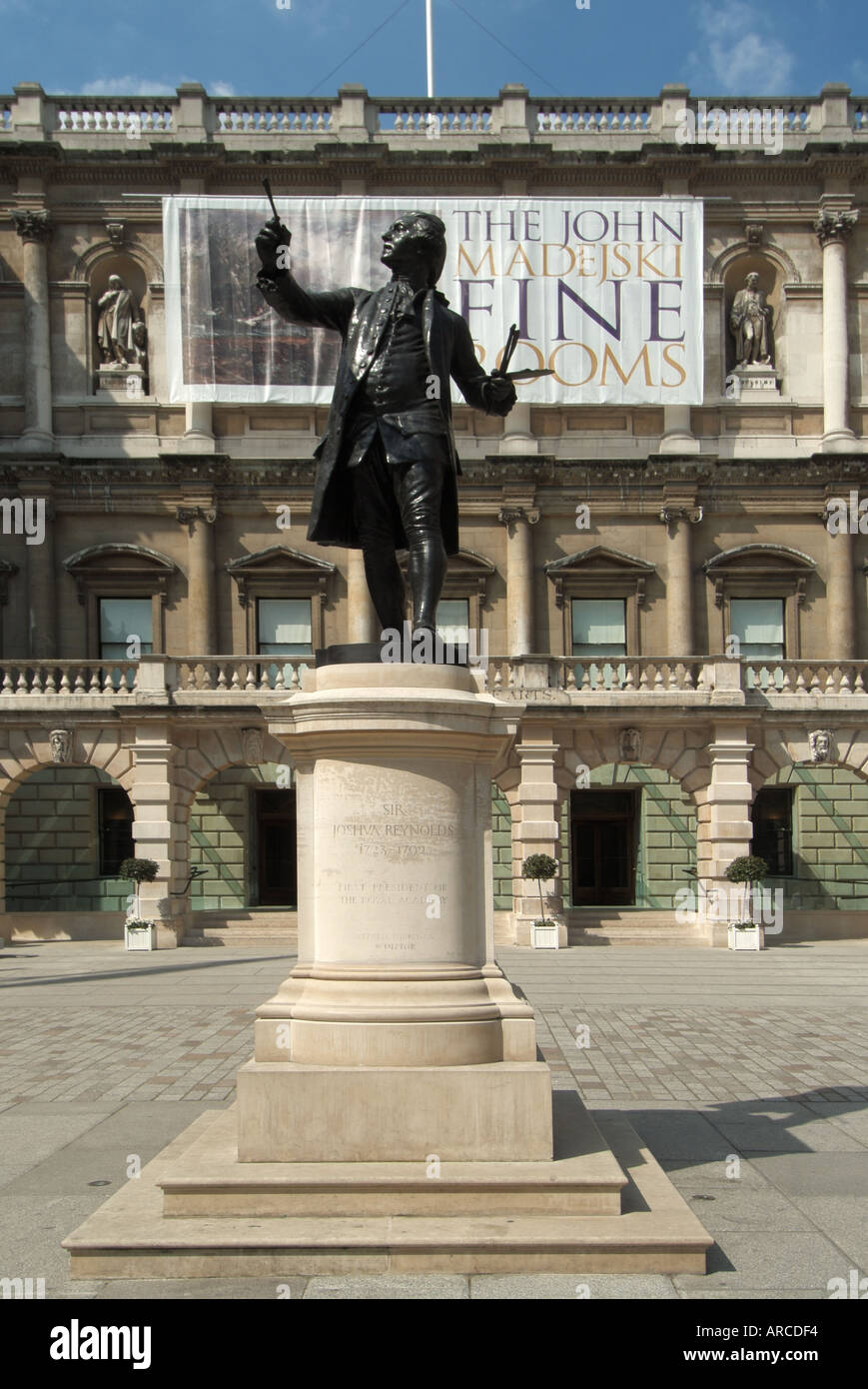 London Royal Academy courtyard with sculpture of Sir Joshva Reynolds first president of the RA and promotional banner Stock Photo