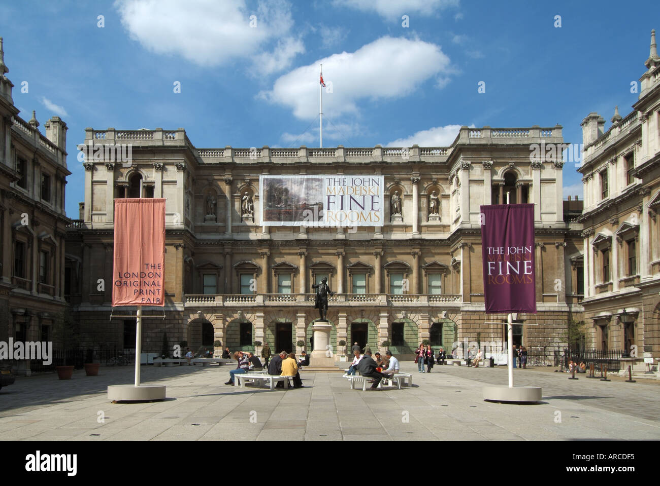 London Royal Academy courtyard with sculpture of Sir Joshva Reynolds with people and various promotional banners Stock Photo