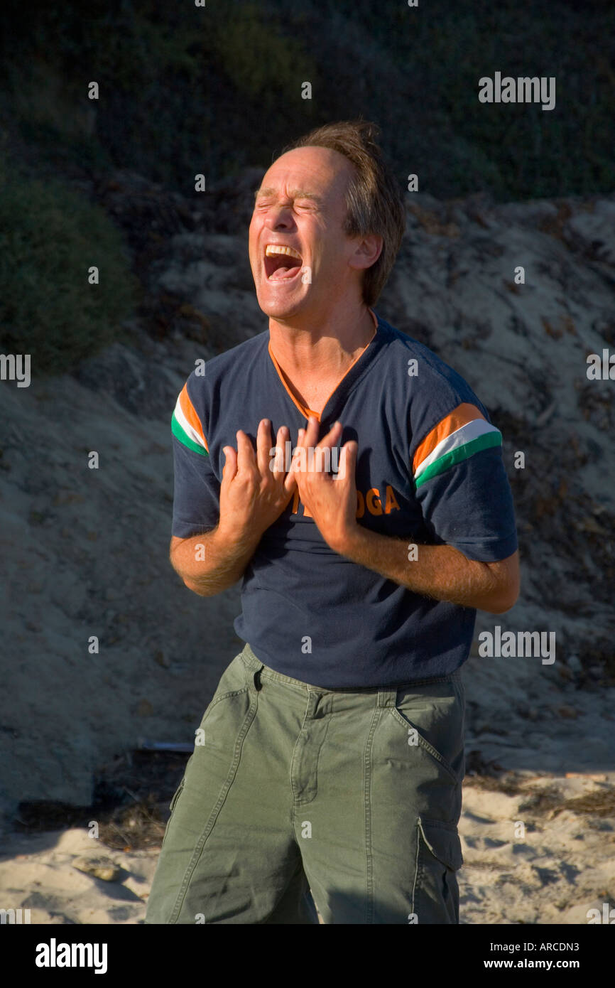 The leader of a Laughter Yoga Club sets an example for his members as they meet by the seaside in Laguna Beach California Stock Photo