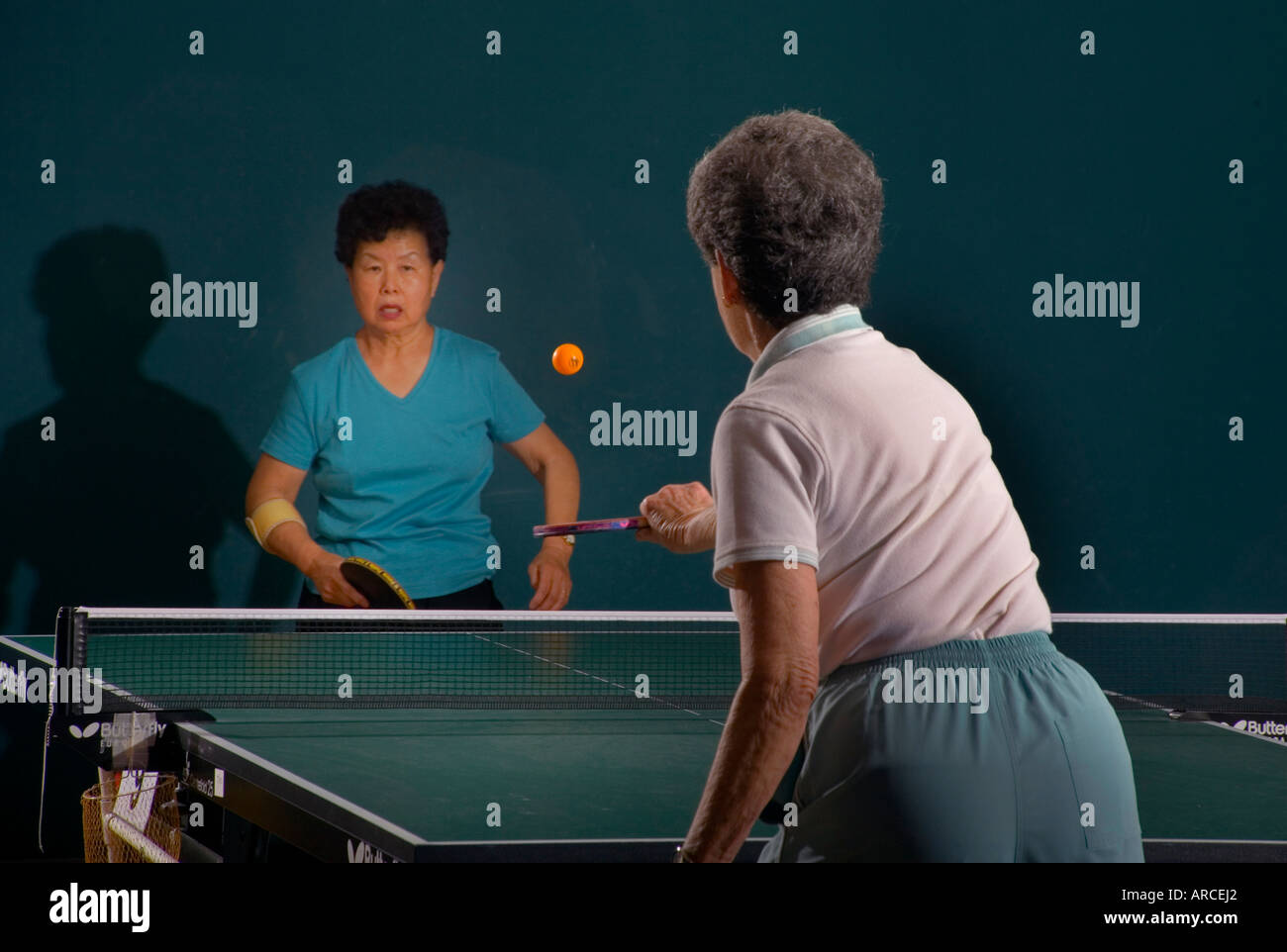 Two women over age 70 play ping pong at a seniors athletic facility