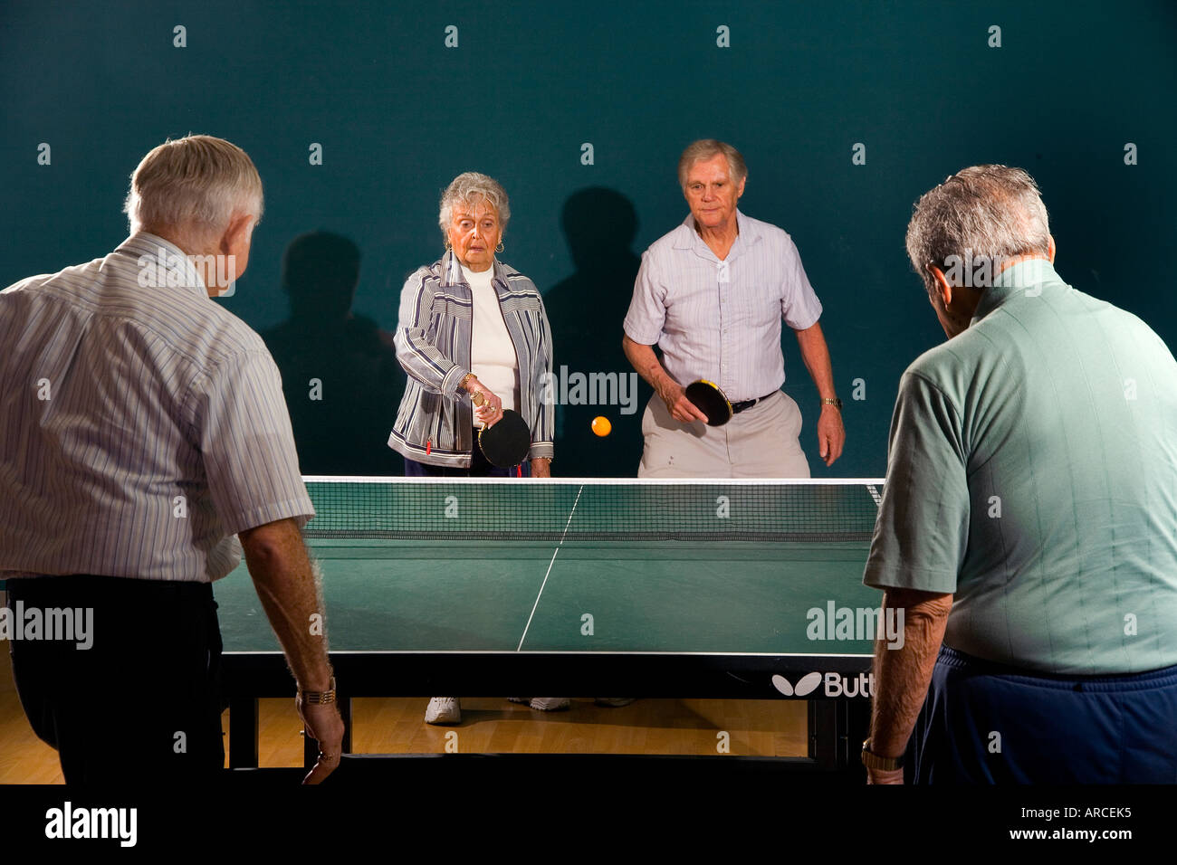 Senior men and women ranging in age from their 70 s to their 90 s play ping pong Stock Photo