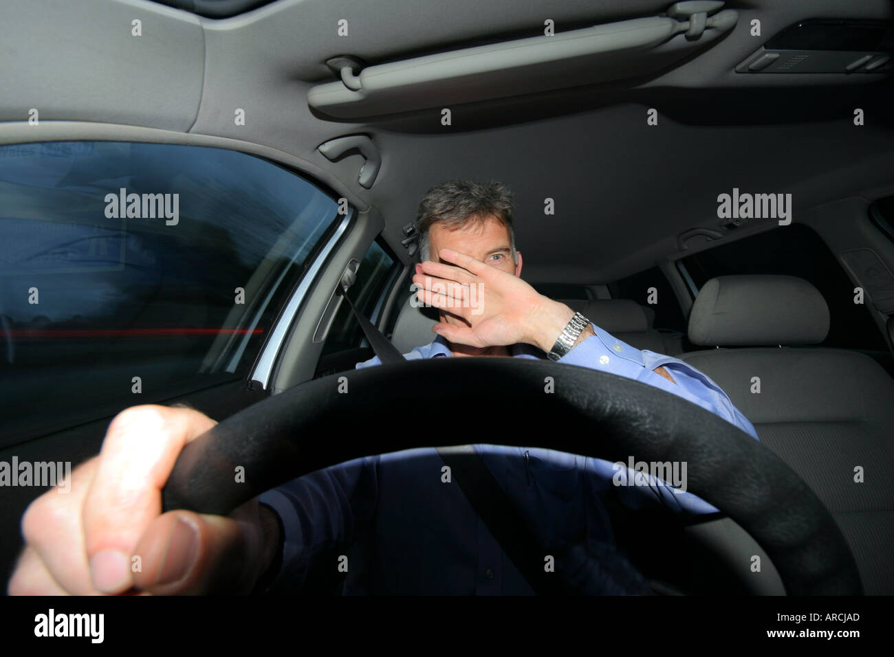 Front view of a man driving a car at night being blinded by