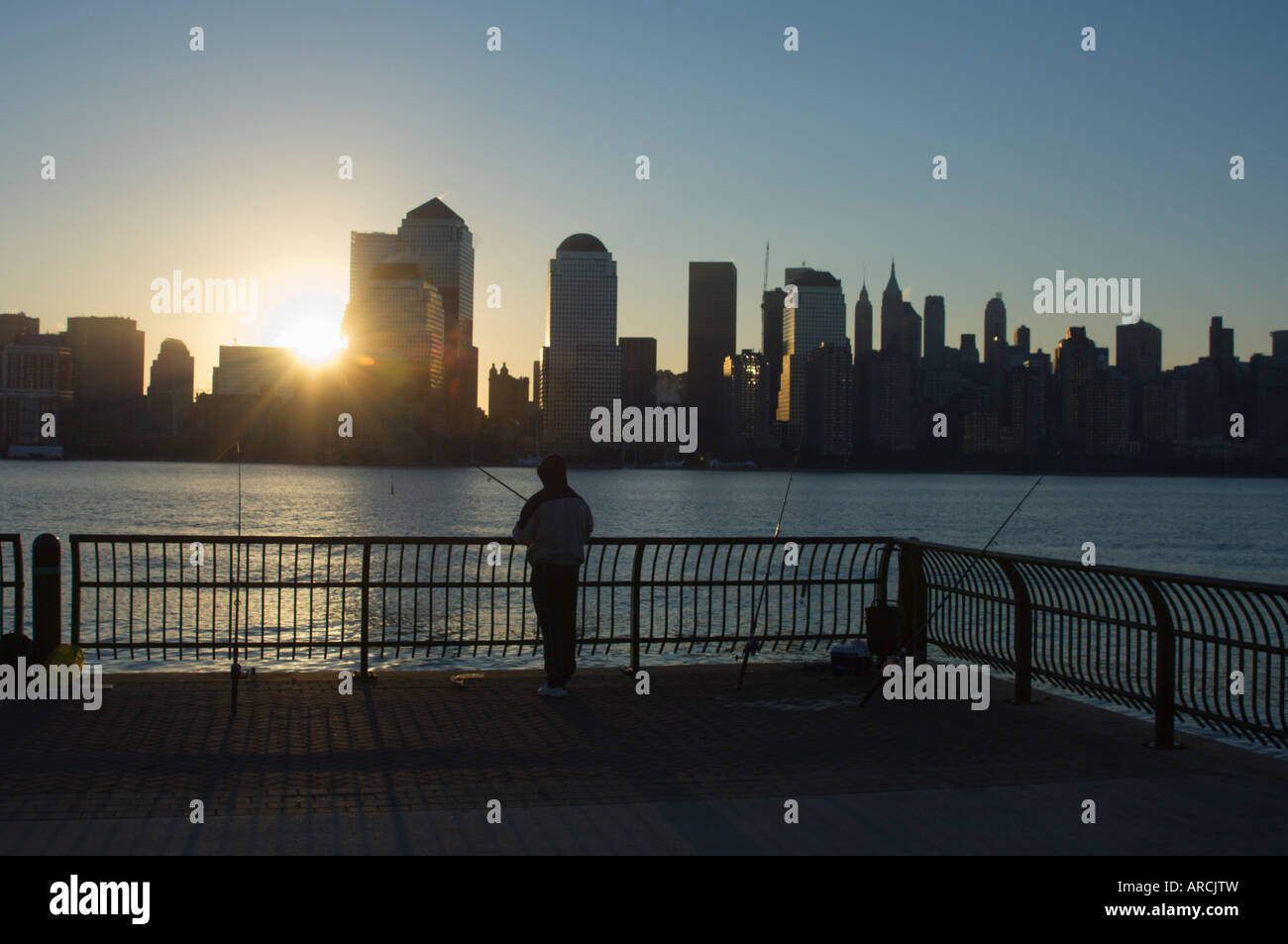 Fisherman fishing from a Jersey City pier at dawn facing the Manhattan skyline, Jersey City, New