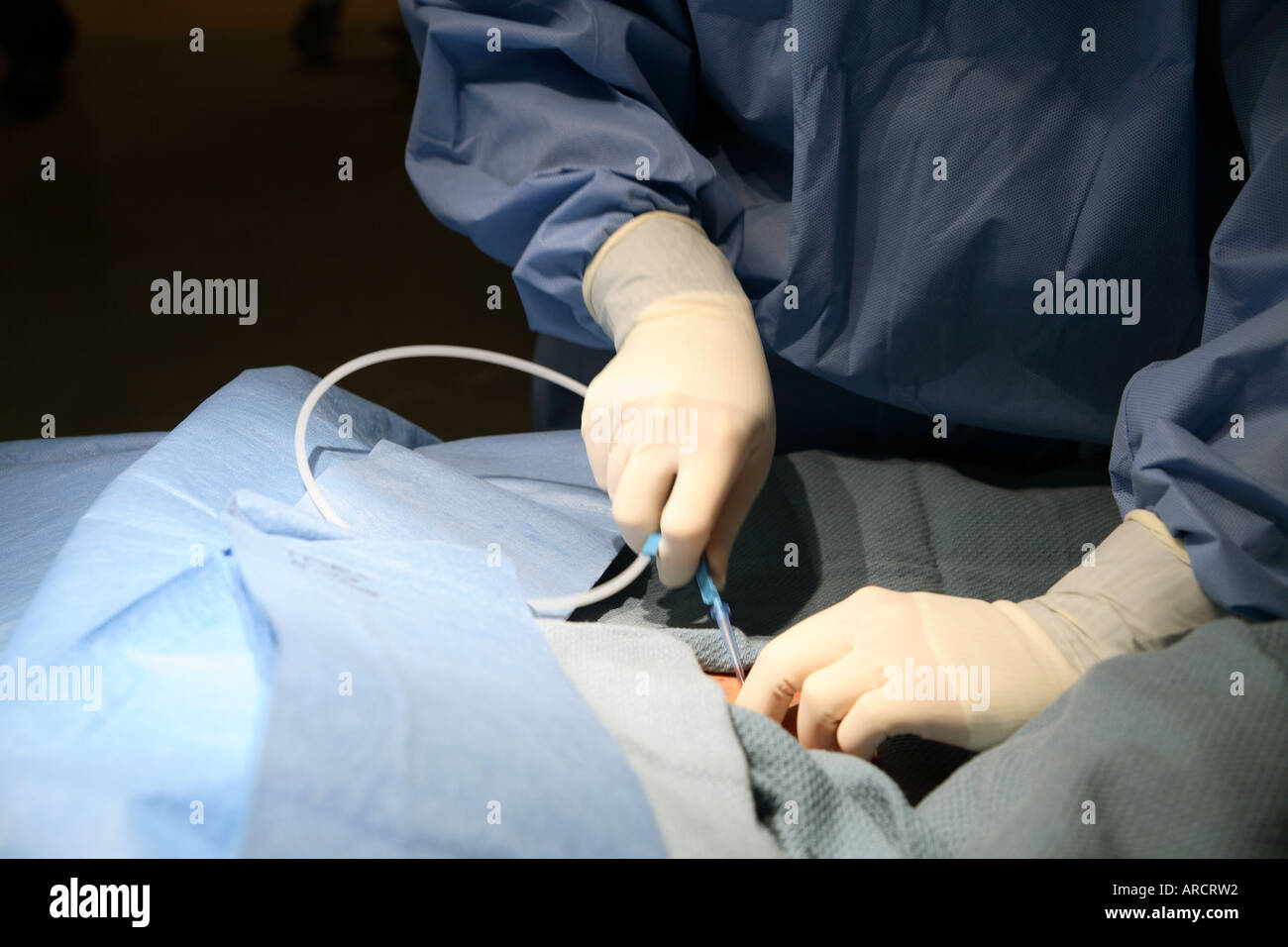 A surgical resident in the intensive care unit (ICU) during the insertion of a right subclavian central venous catheter. Stock Photo