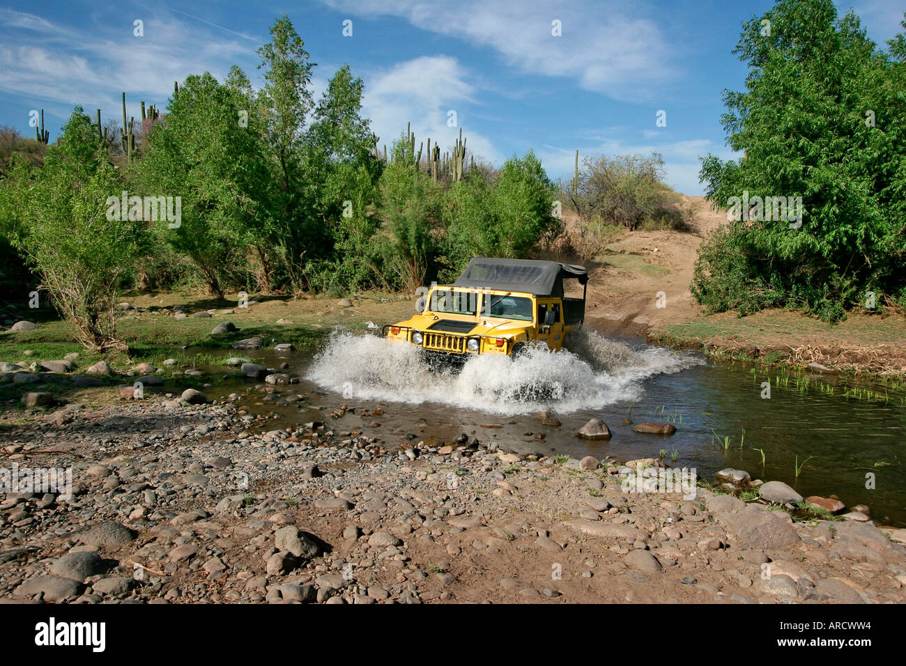 Hummer vehicle splashes through a stream in Arizona desert, USA Stock Photo