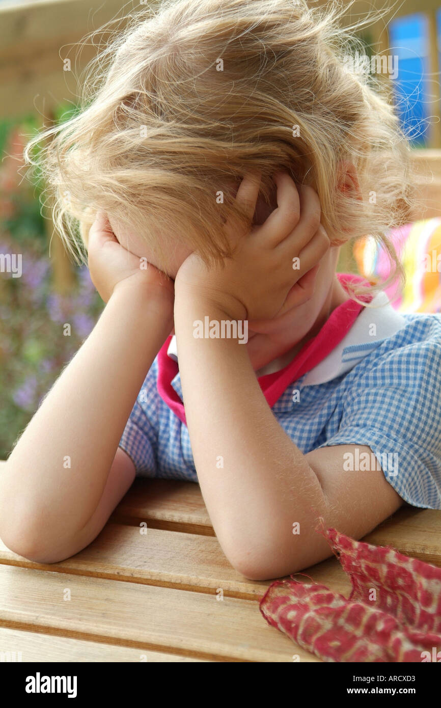 Little blonde girl with head in hands Stock Photo