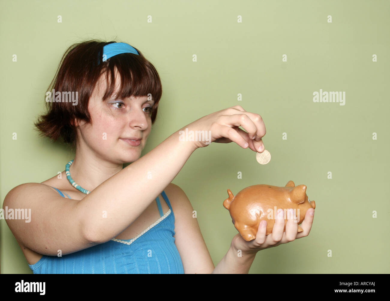 A girl inserting a coin in the piggy bank Stock Photo - Alamy